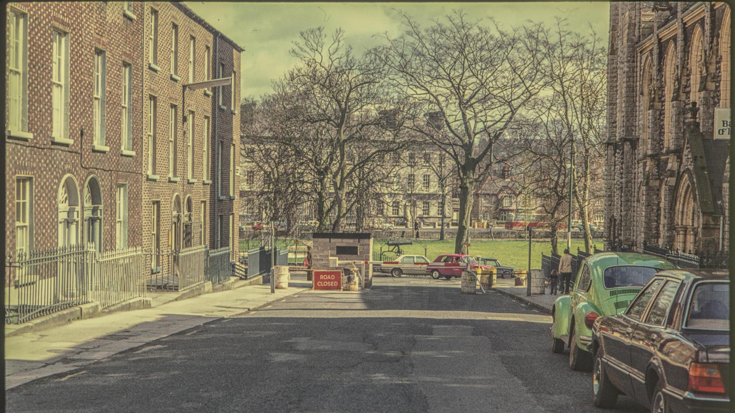 A digitalised photo from a film of a road end. A road closed sign is at the top and red brick buildings line the street.