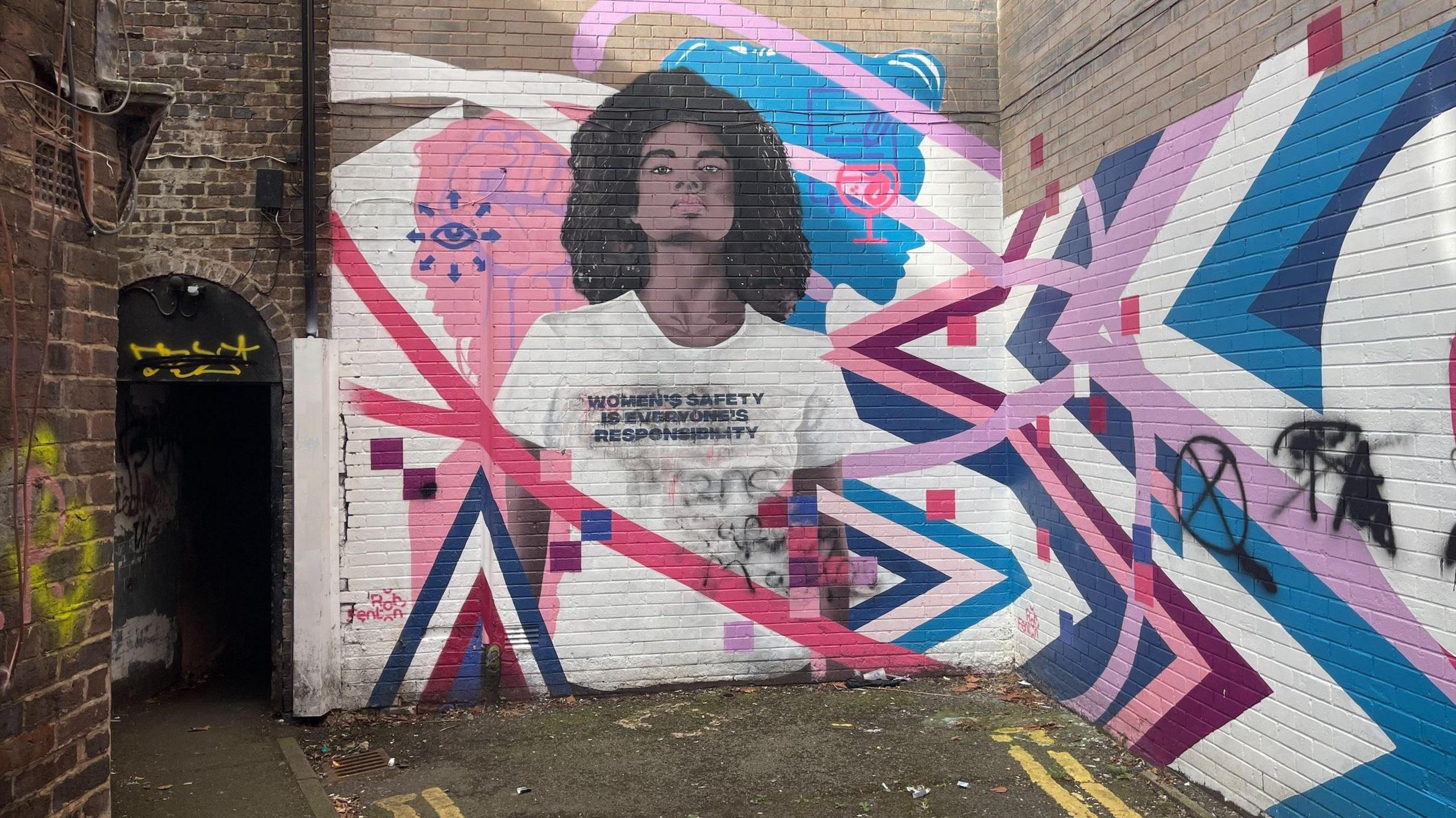 A mural of a woman wearing a white t shirt with the words women's safety is everyone's responsibility. 