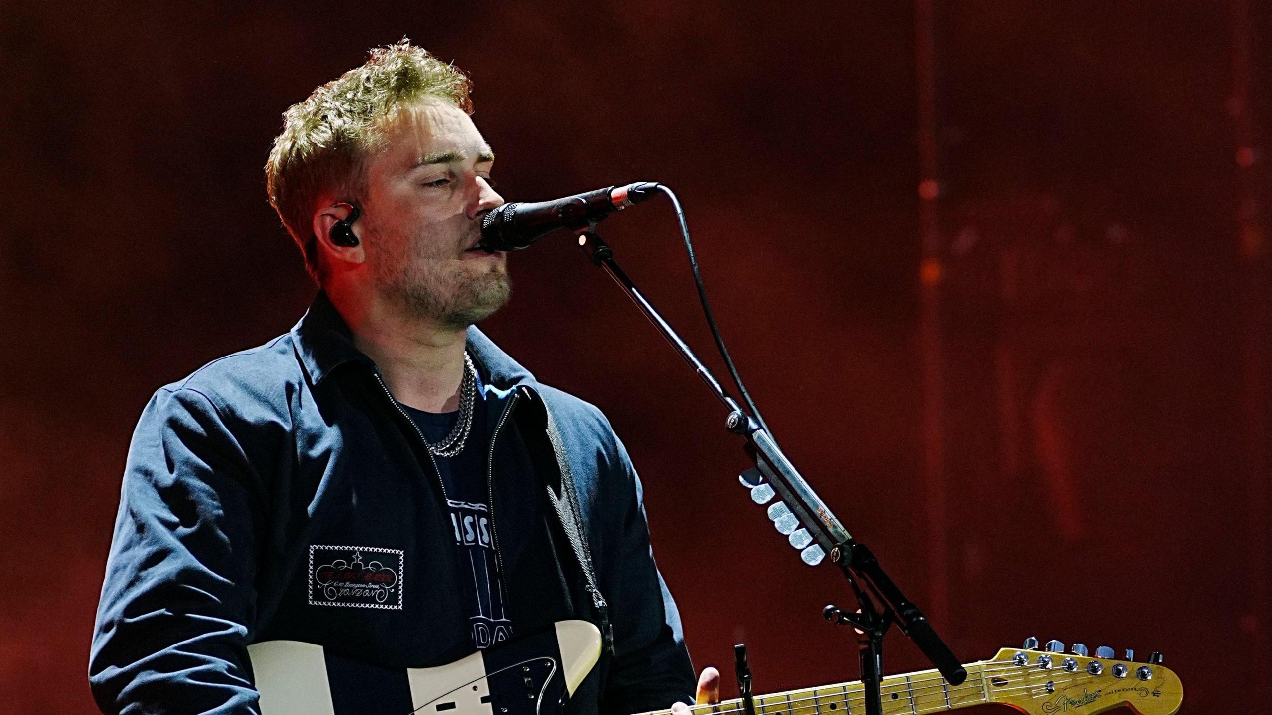Sam Fender performing at Big Weekend, singing into a microphone while playing the guitar.