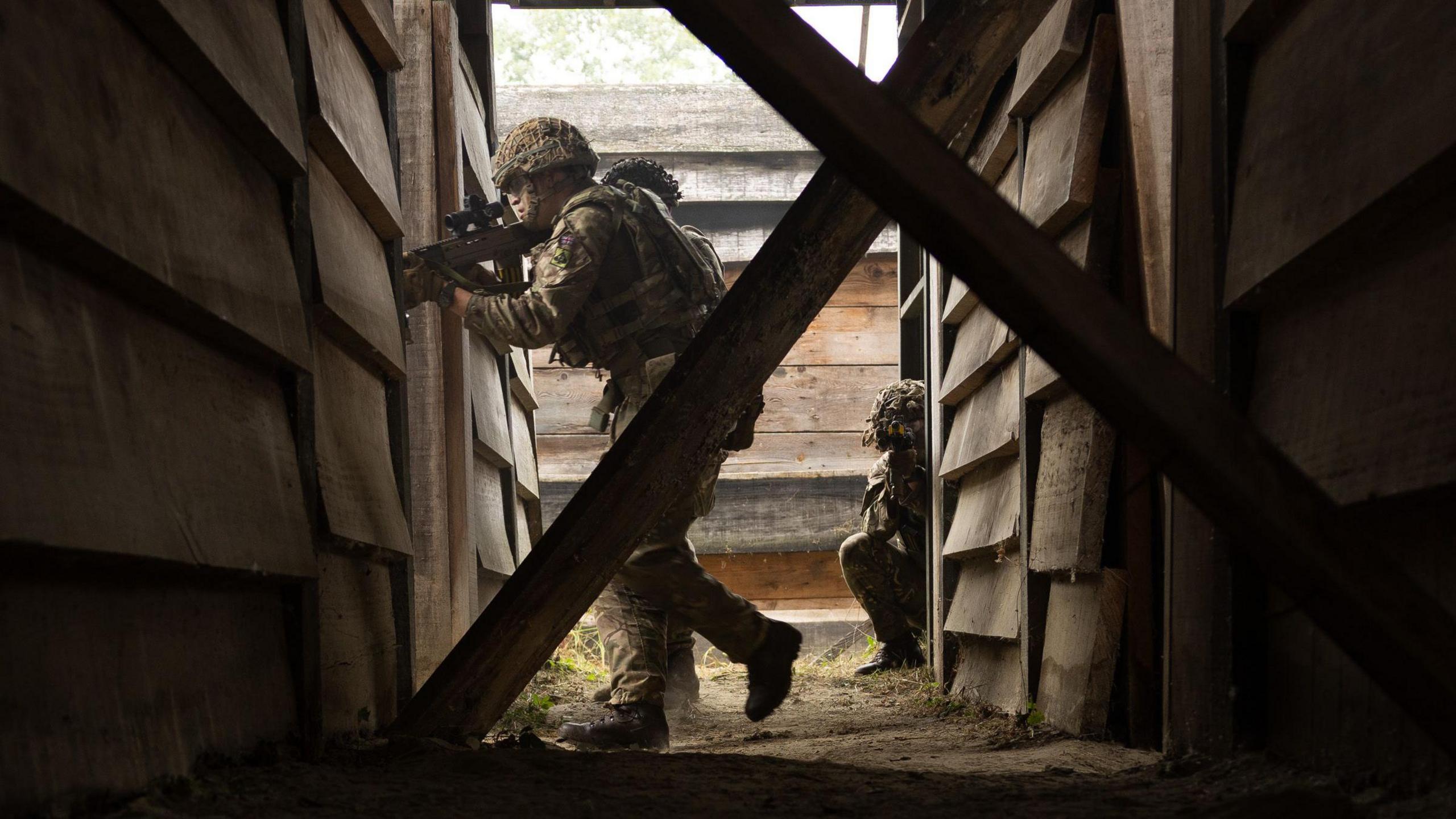 A reservist army officer holding an unloaded gun, searching a settlement as part of a training exercise in Croatia