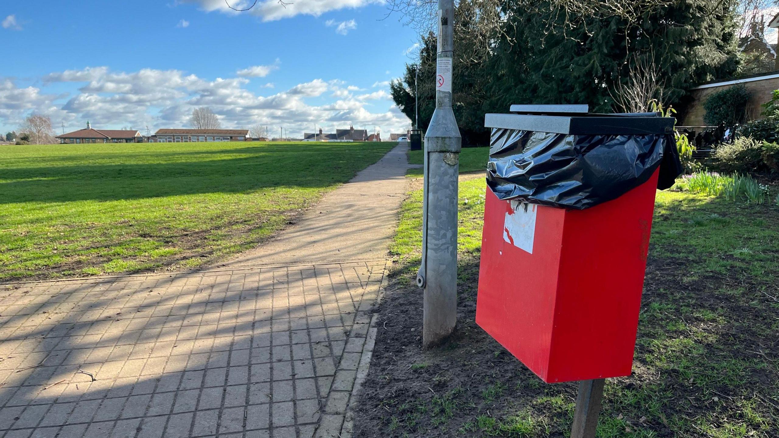 A red dog poo bin in Keyworth recreation ground. 