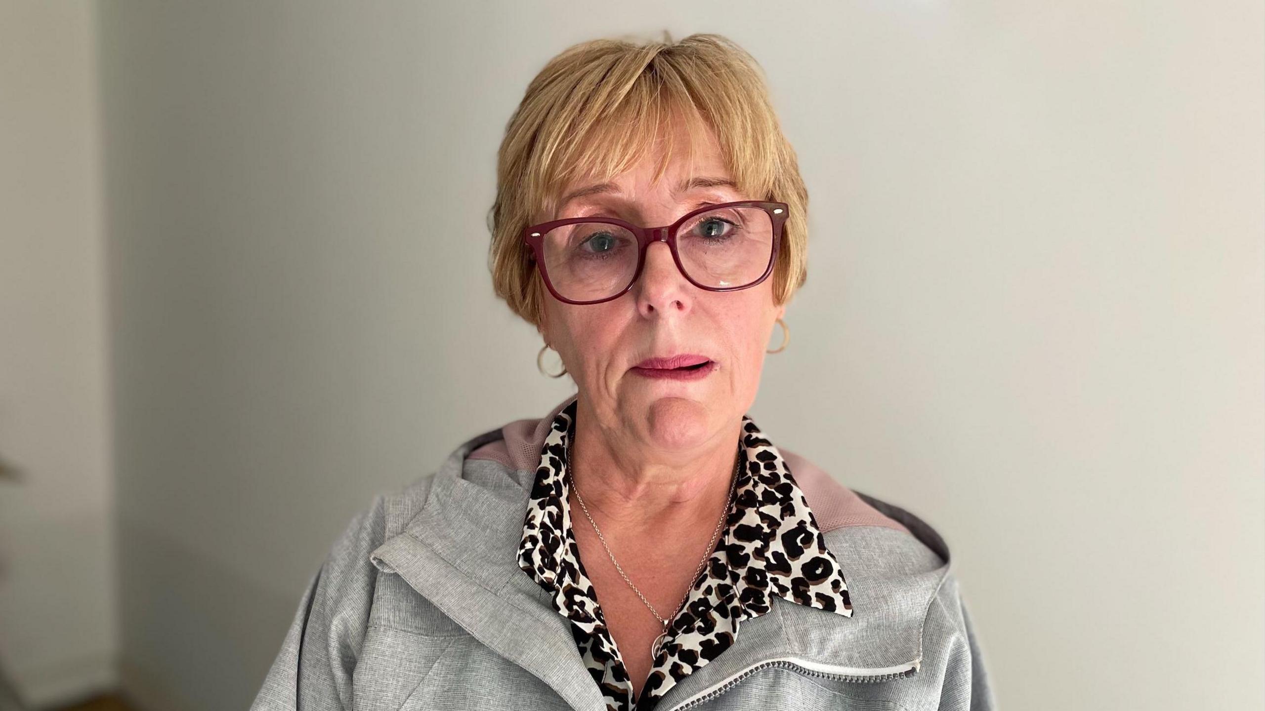 Llun o Kim Fjaelberg yn edrych ar y camera'n drist. Mae'n gwisgo sbectol a siwmper llwyd.
