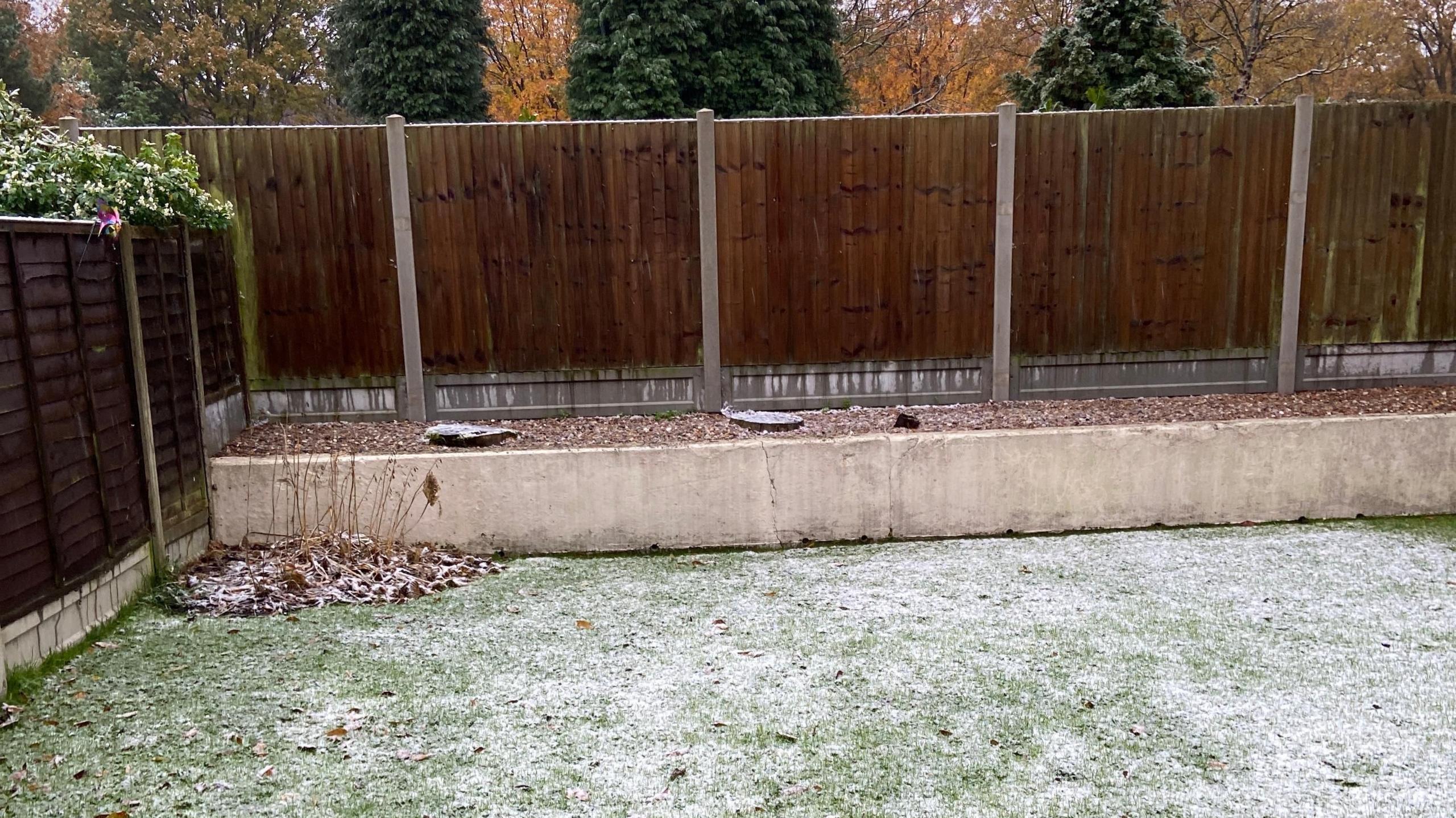 A tiered garden which has a very light dusting of snow settled on the grass