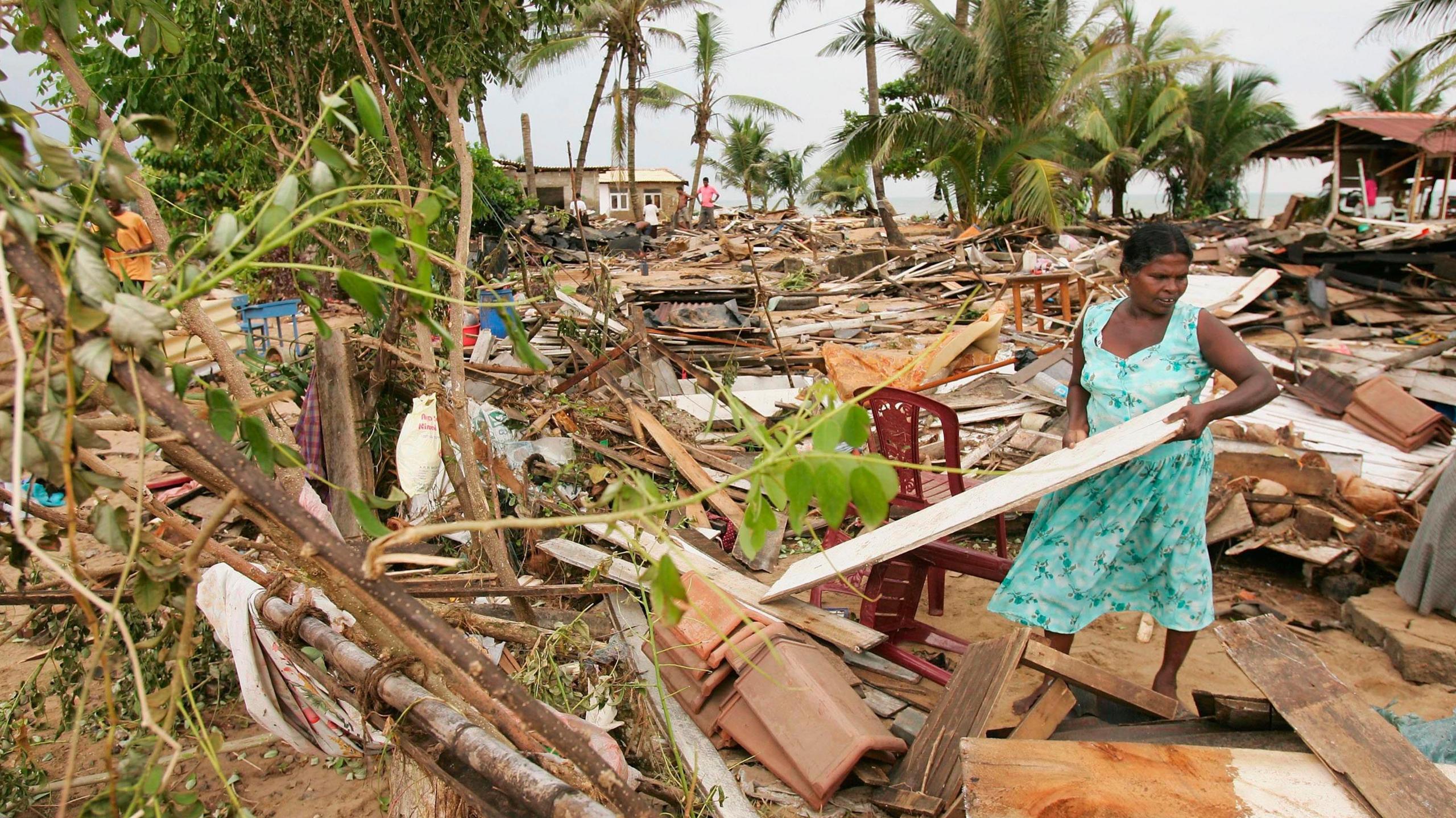 Dynes yn clirio llanast o'r man lle safai ei chartref yn Sri Lanka