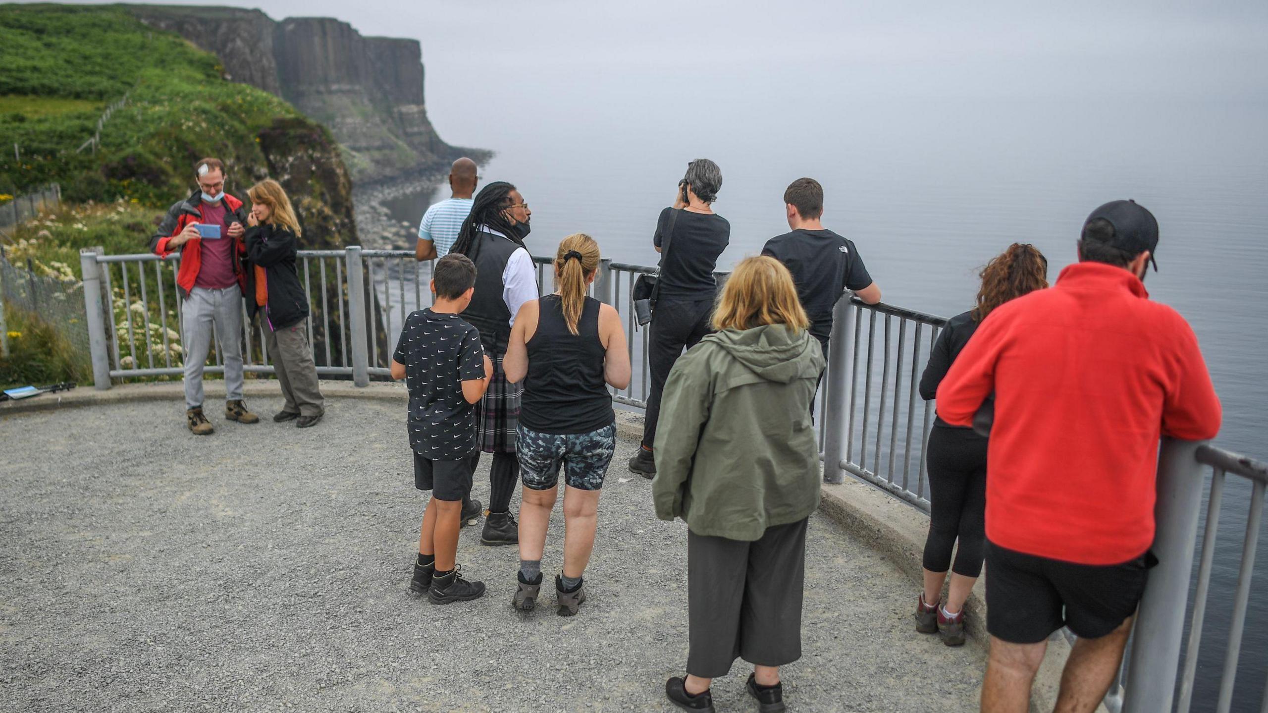 A group of tourists gathered at a viewpoint at Kilt Rock on Skye.