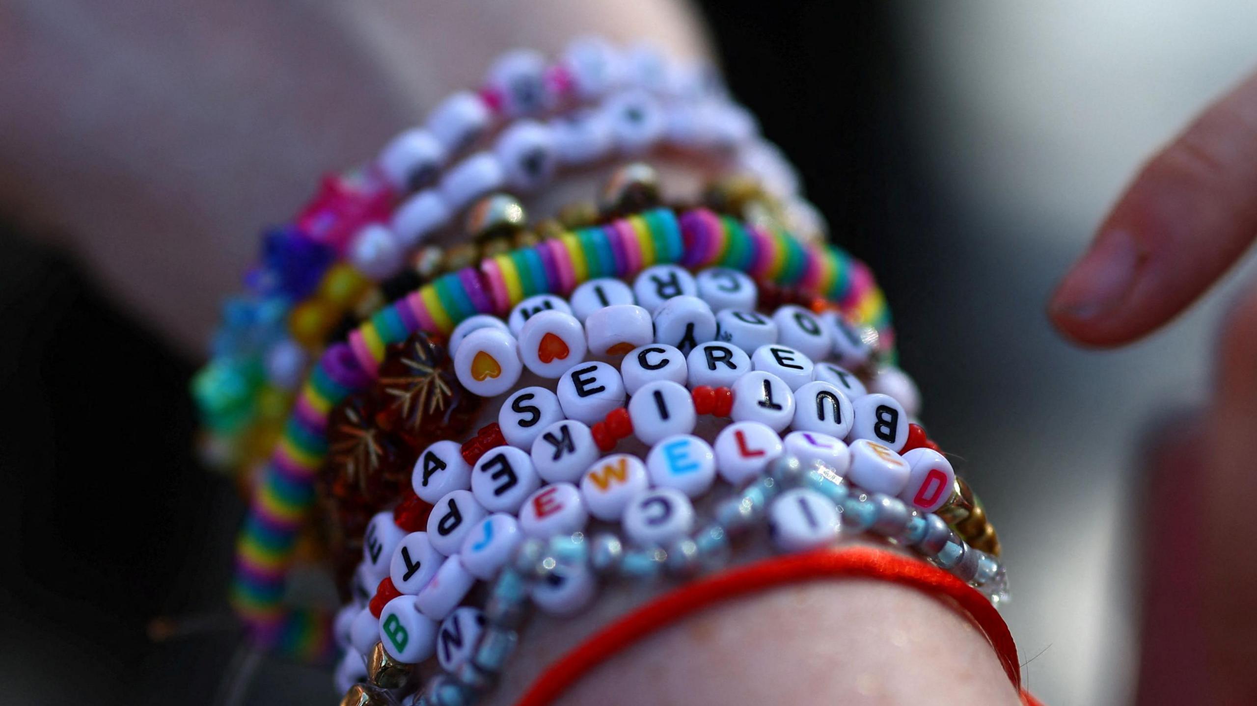 A person wearing homemade friendship bracelets with different Taylor Swift references