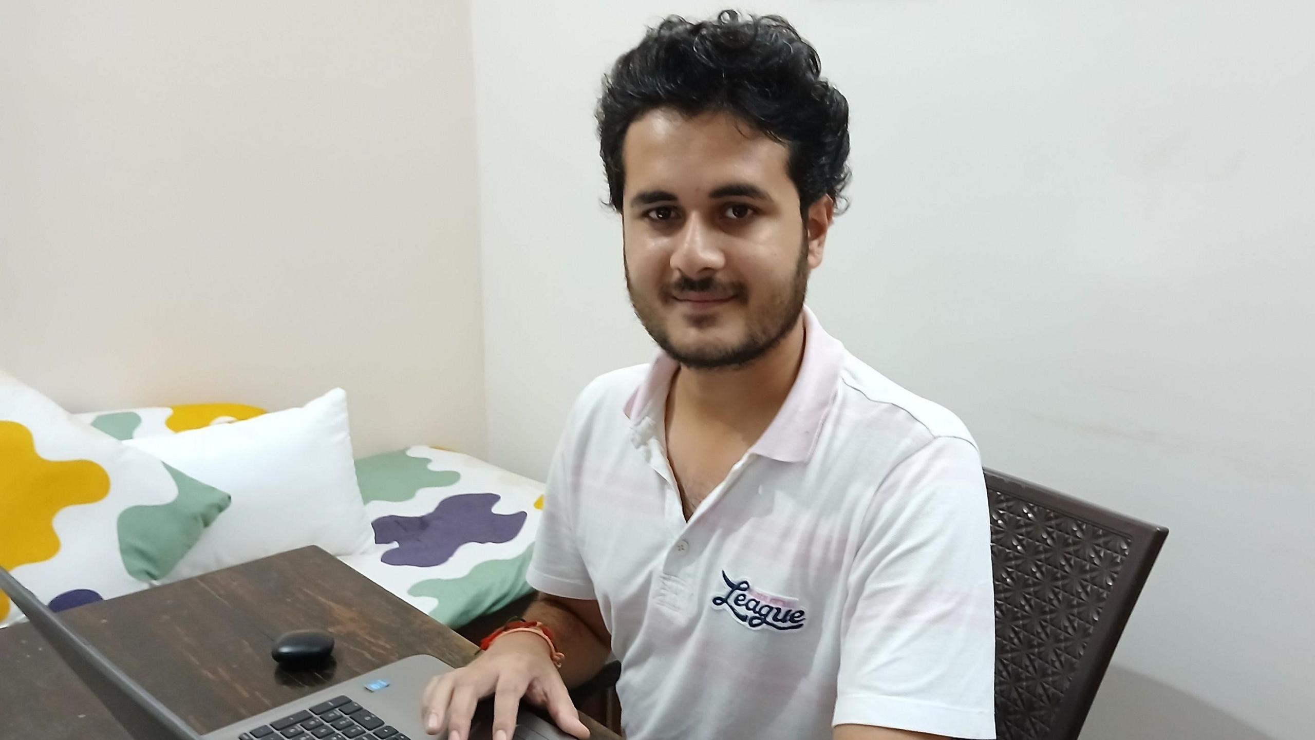 Anurag Garg sitting at his computer wearing a white shirt.