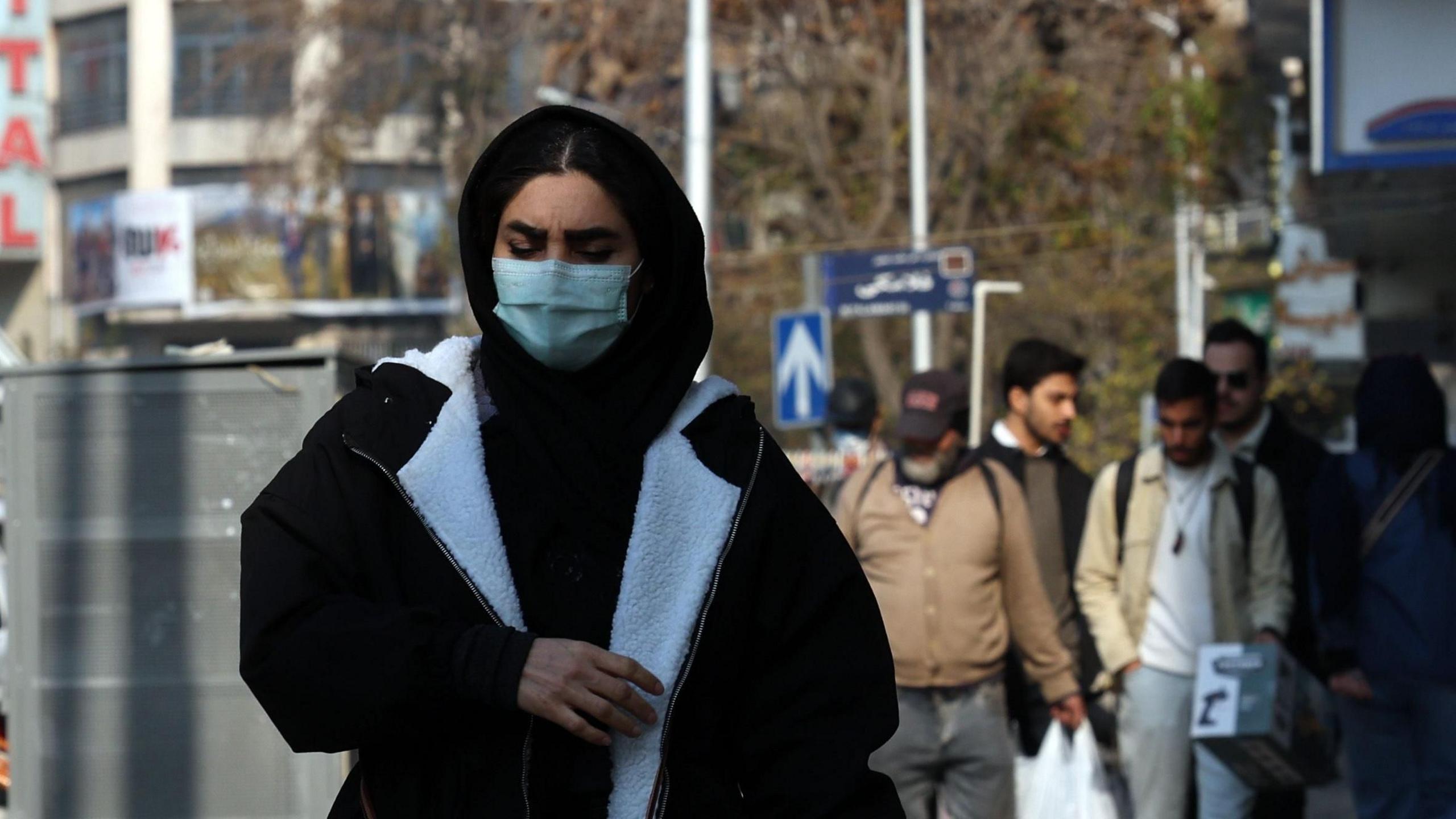 An Iranian woman wearing face mask walks in a street in Tehran, Iran