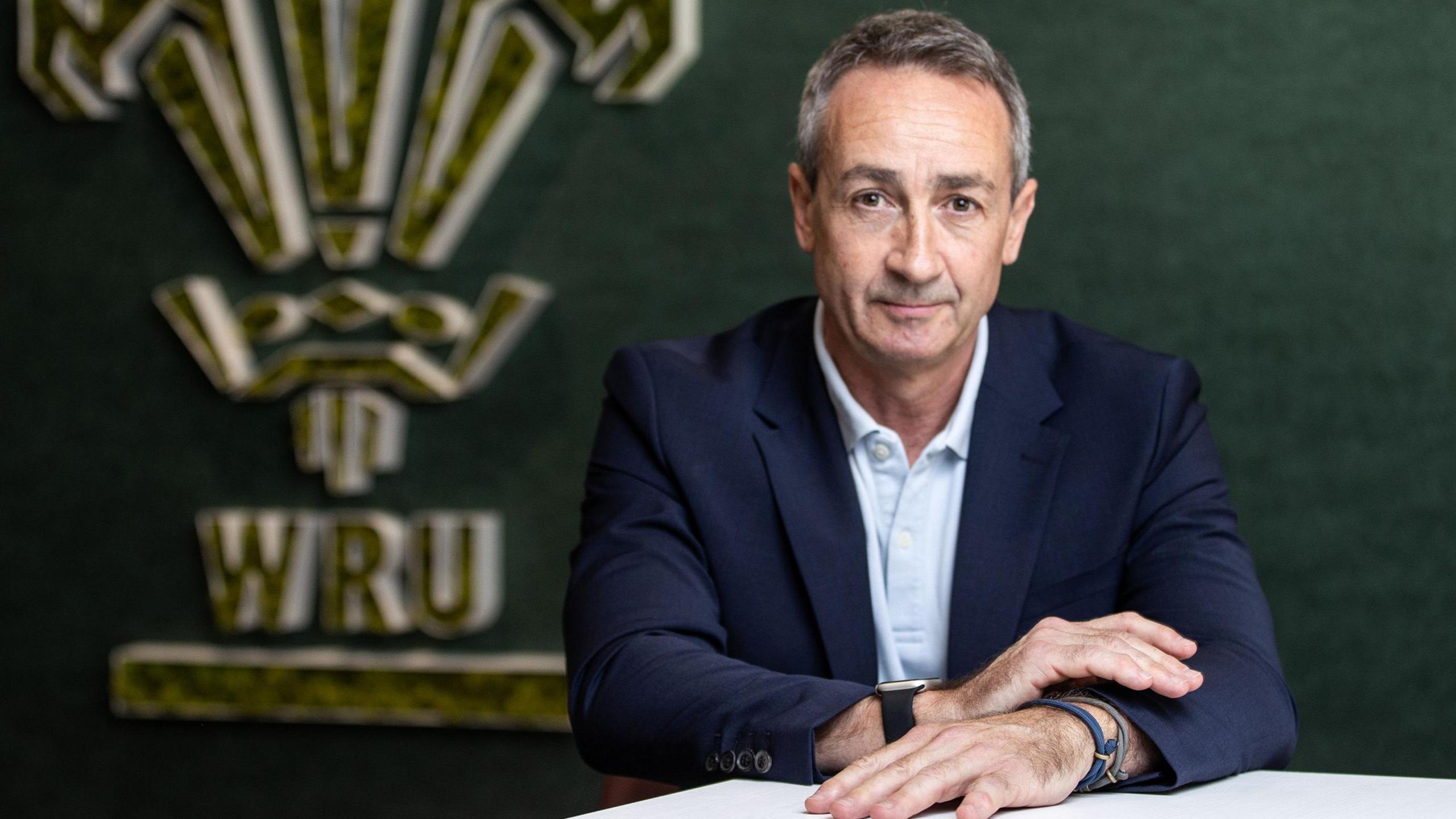 Dave Reddin, who took over as Welsh Rugby Union director of rugby and head of performance in the summer 2025,  in front of a WRU logo