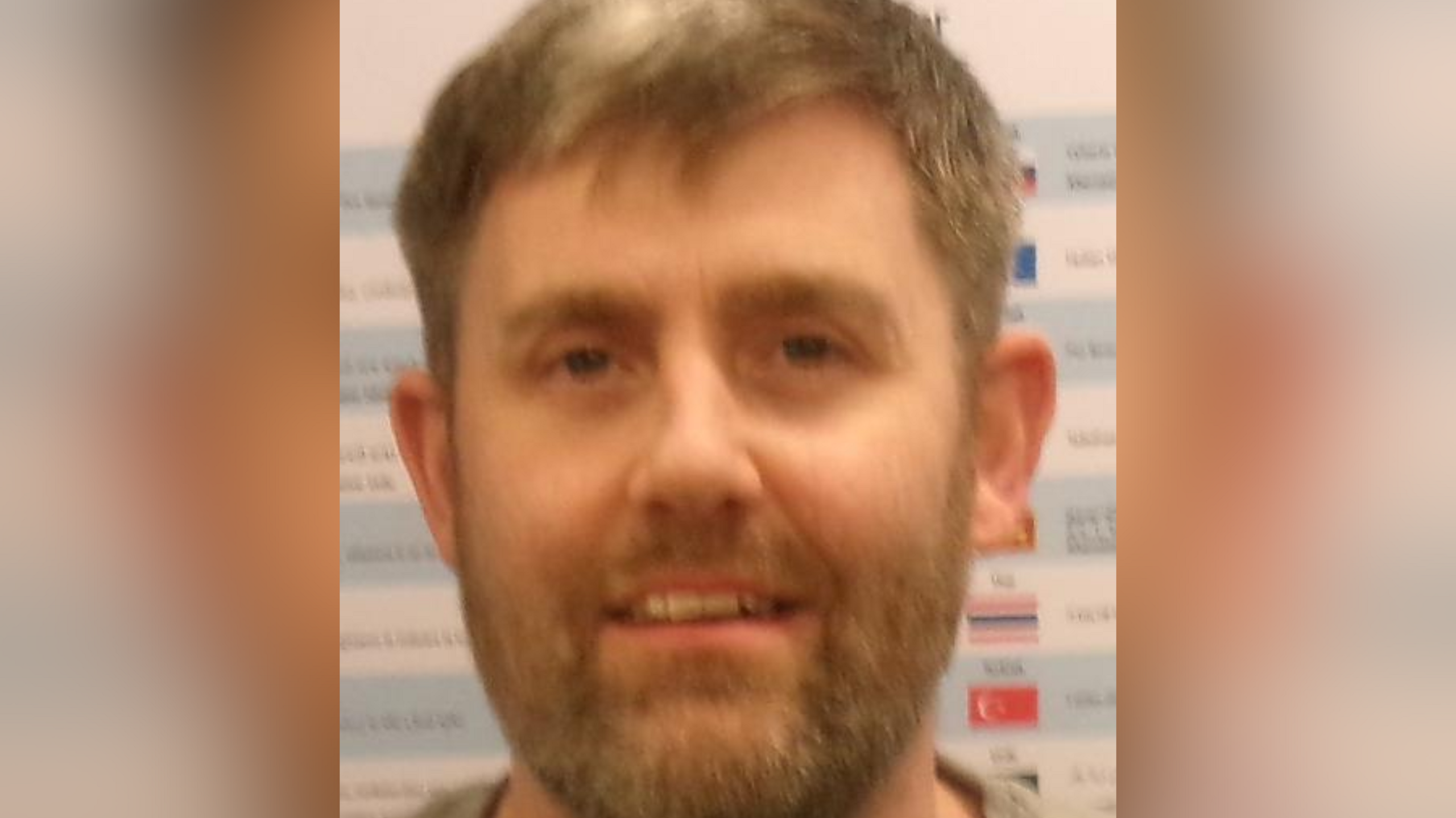 A headshot of Jamie Sherfield, has a short haircut and facial hair. He is looking directly into the camera. 