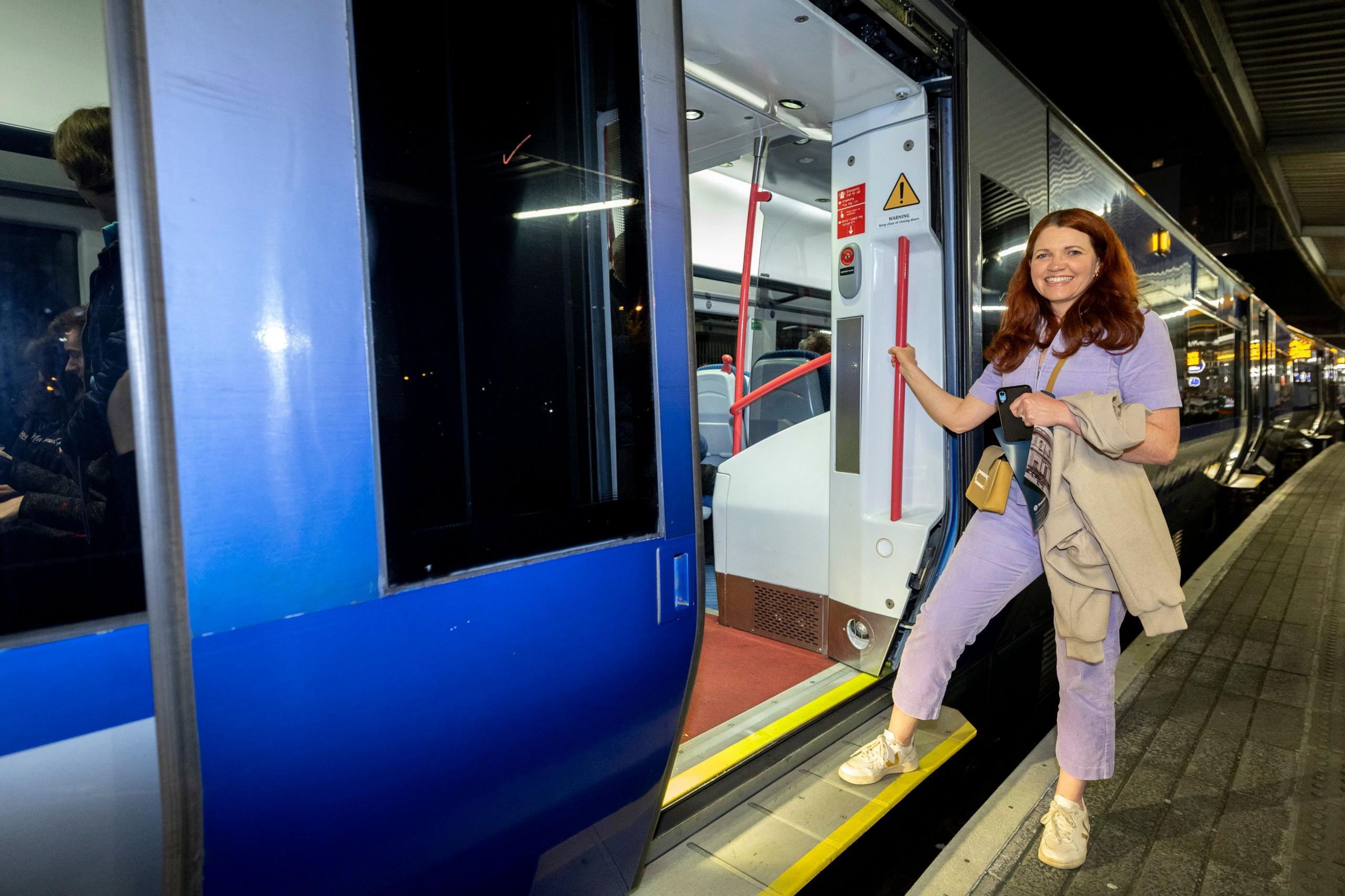 a woman in a purple jumpsuit stepping onto a train