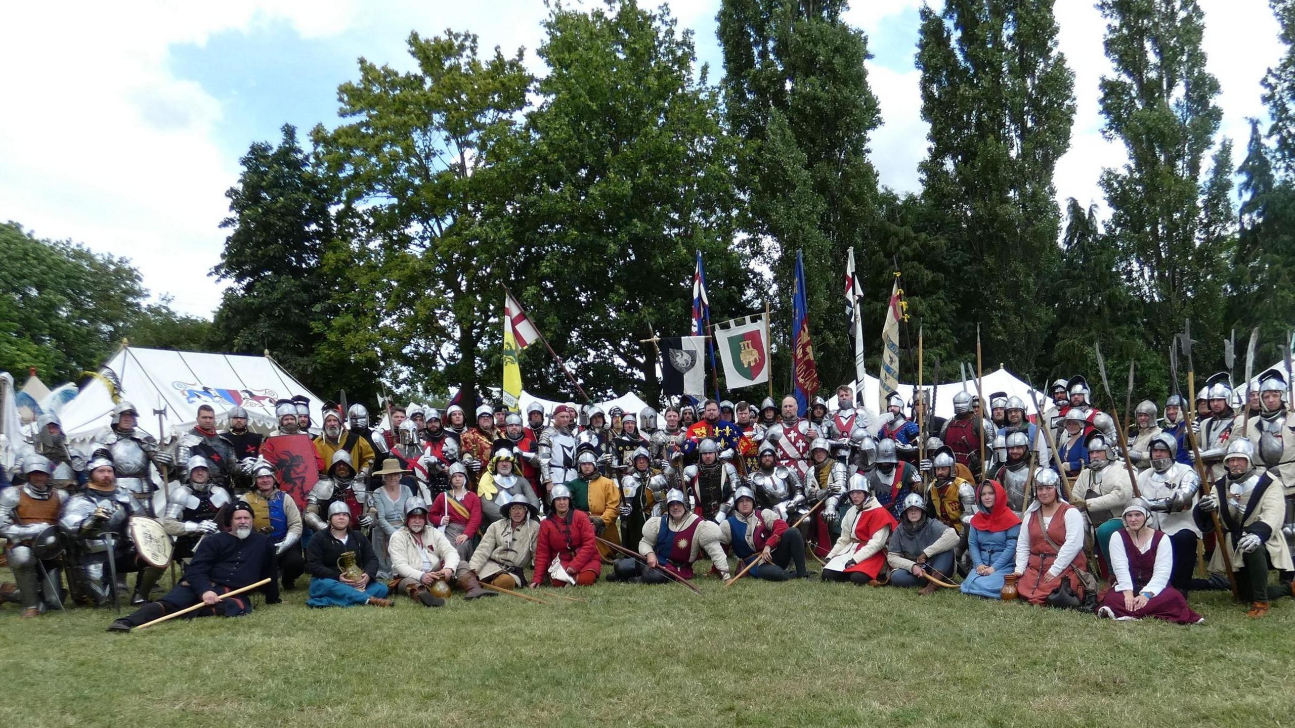 A large group in medieval costume posing for a photo outside