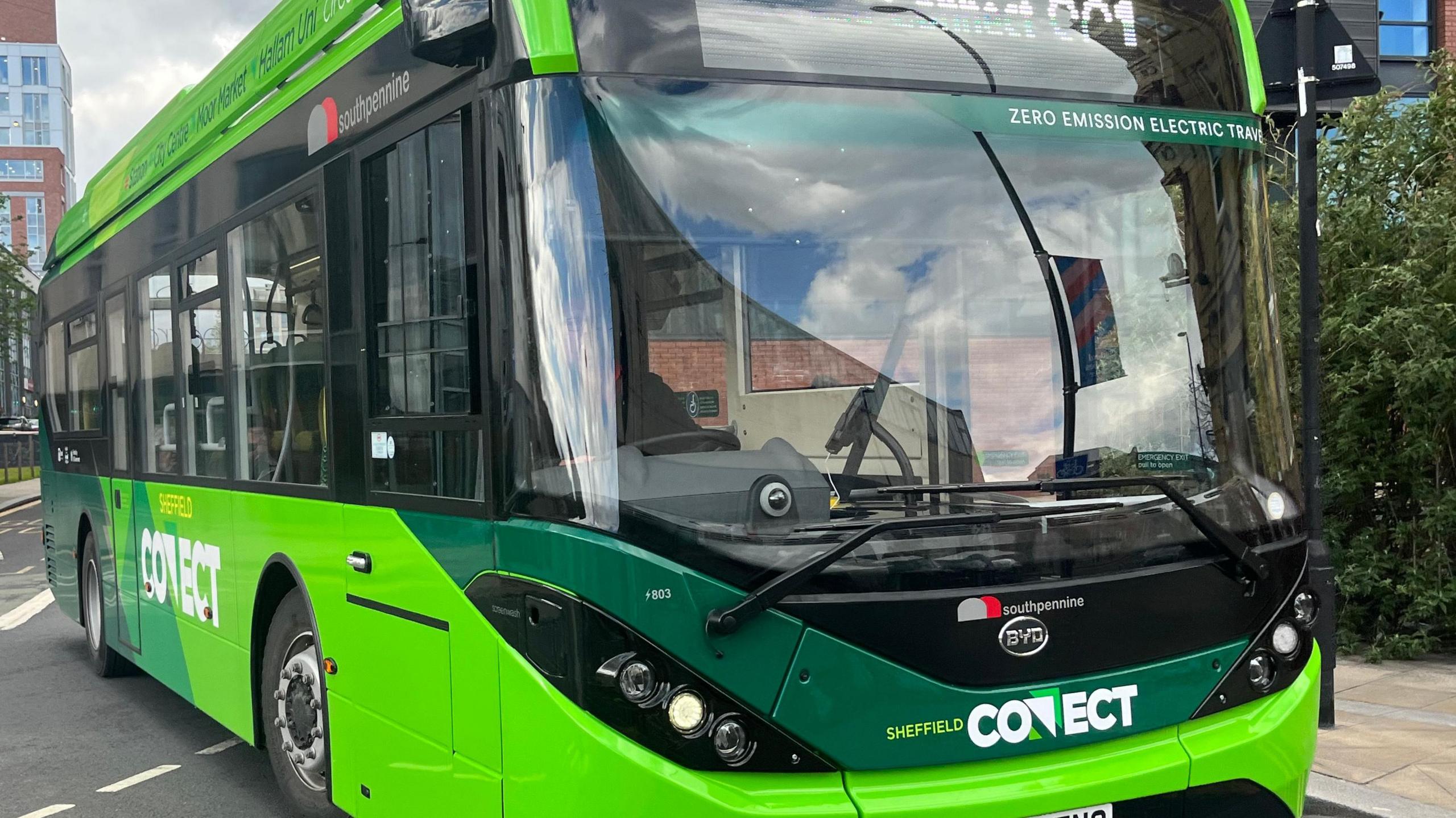 A green bus, seen from an angle at the front. The bus says Sheffield Connect on the front and above the window on the front it says Zero Emission Electric Travel.