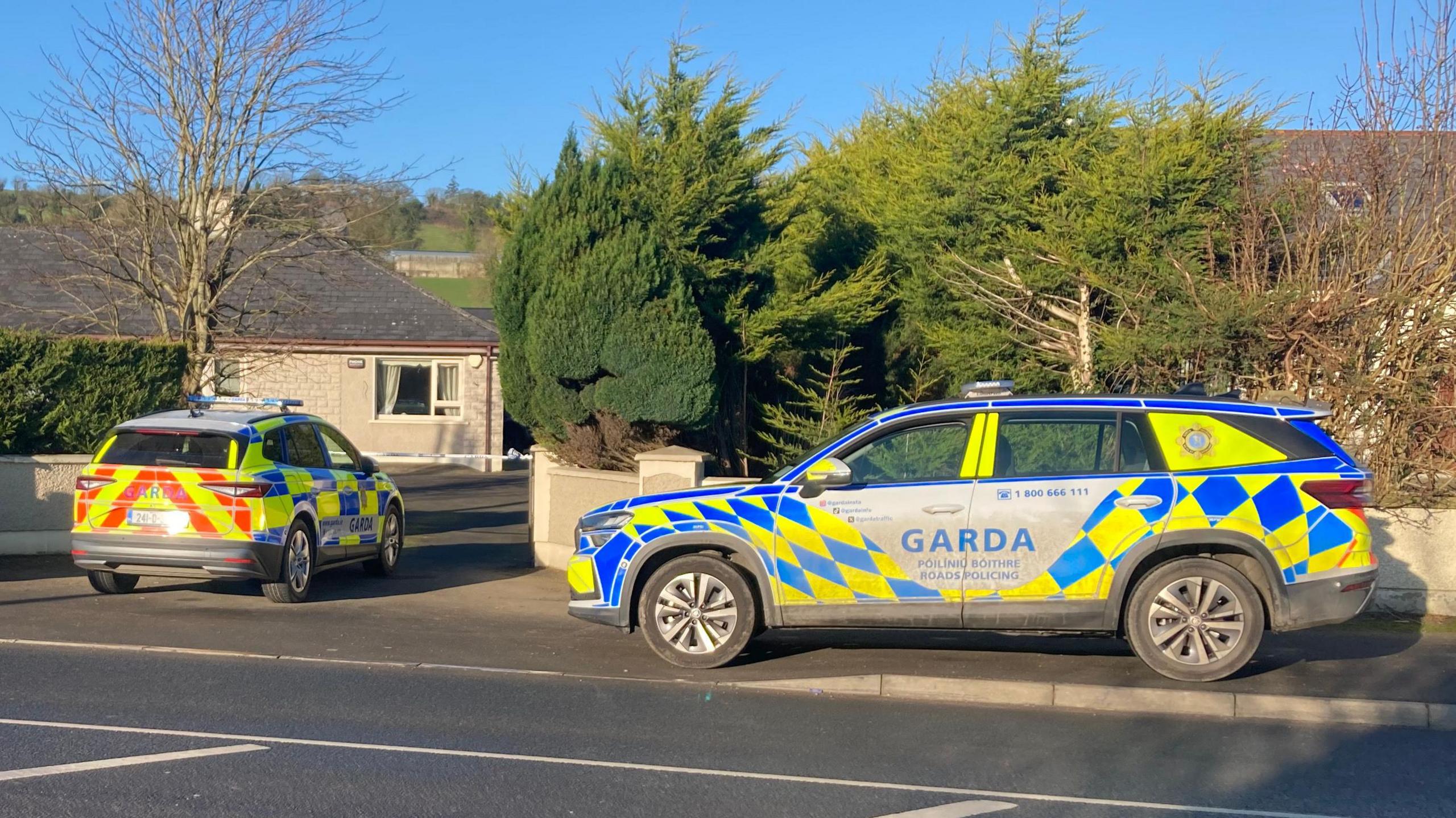 Two garda cars at the house. A police cordon is up at the gate to the house