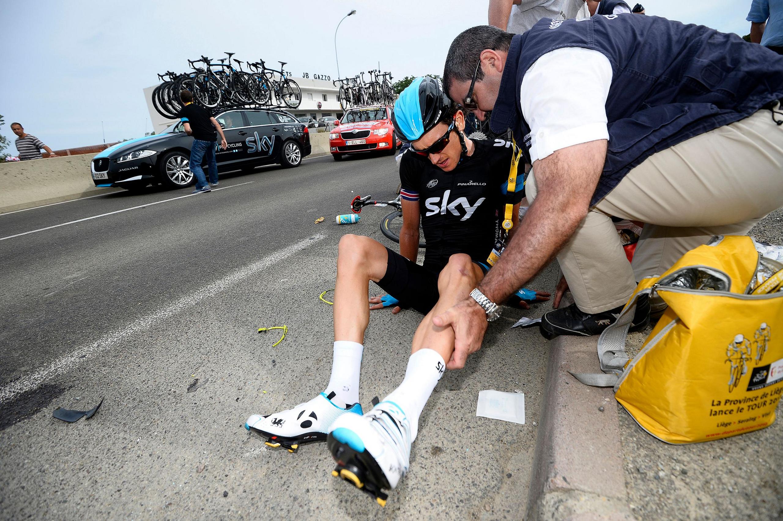 Geraint Thomas having an injury assessed by the side of the road