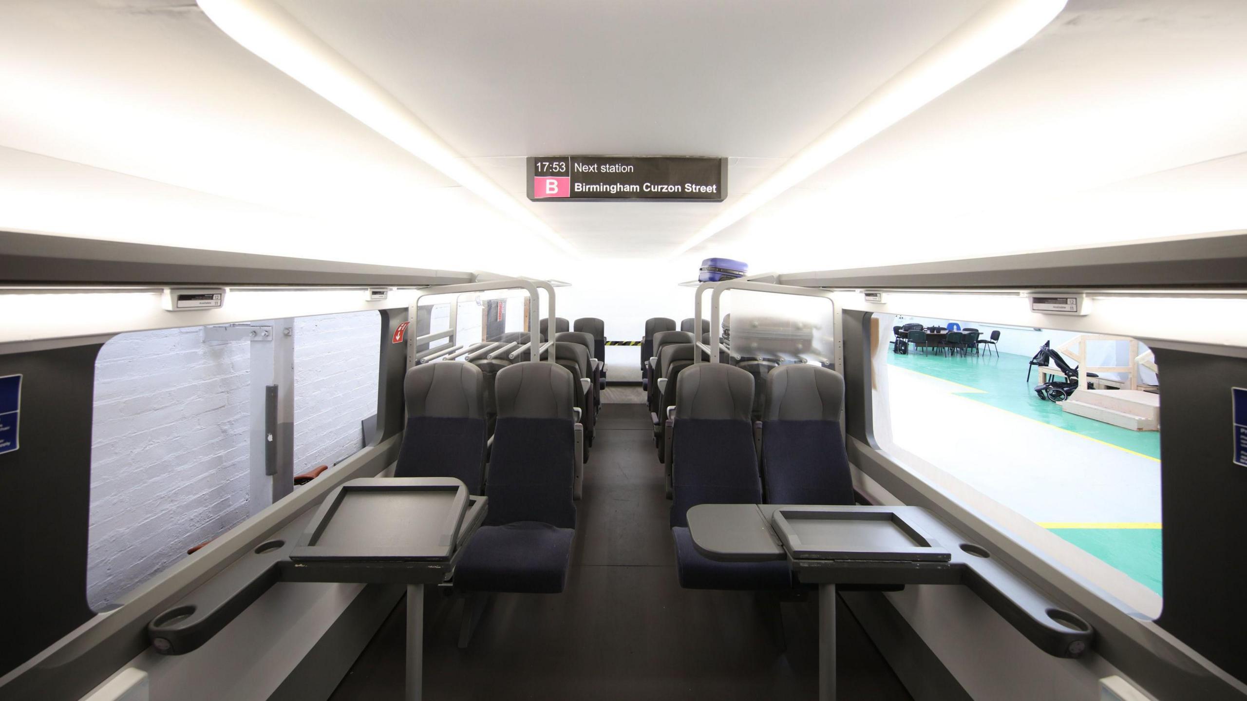 Inside the HS2 carriage which has a modern look with white ceilings and rows of seats with grey tables