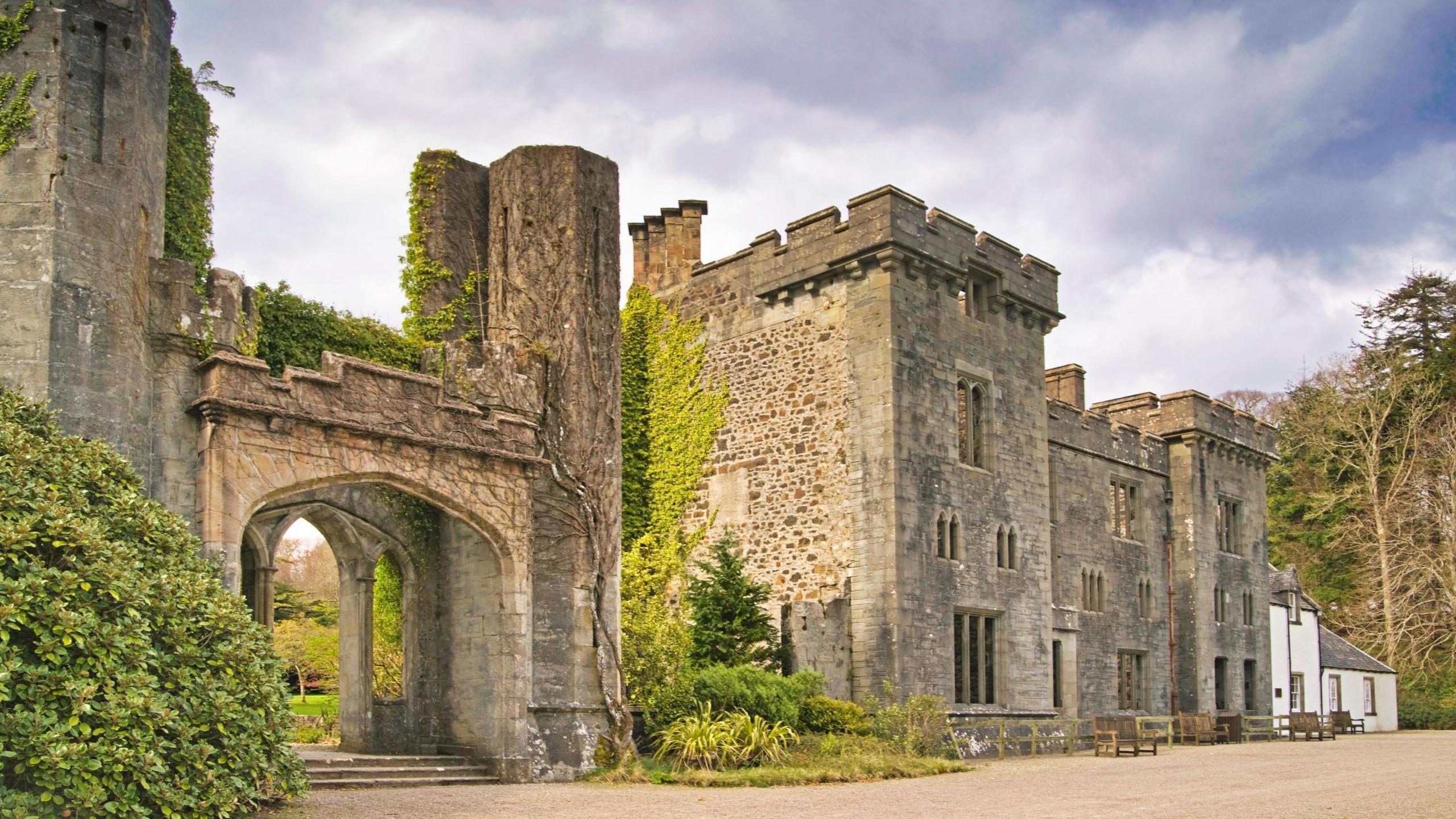 Skye's Armadale Castle is a ruin. There is an entrance with steps and a stone arch and large turreted property with narrow windows.