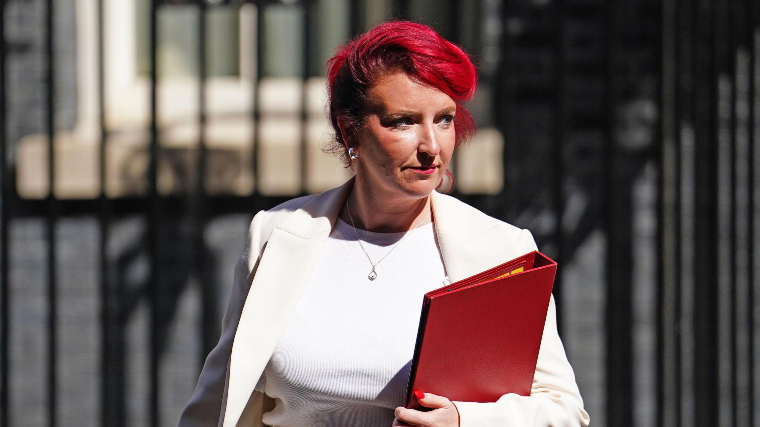 Transport Secretary Louise Haigh, wearing a white top and white jacket, walking in Downing Street whilst holding a red ministerial folder