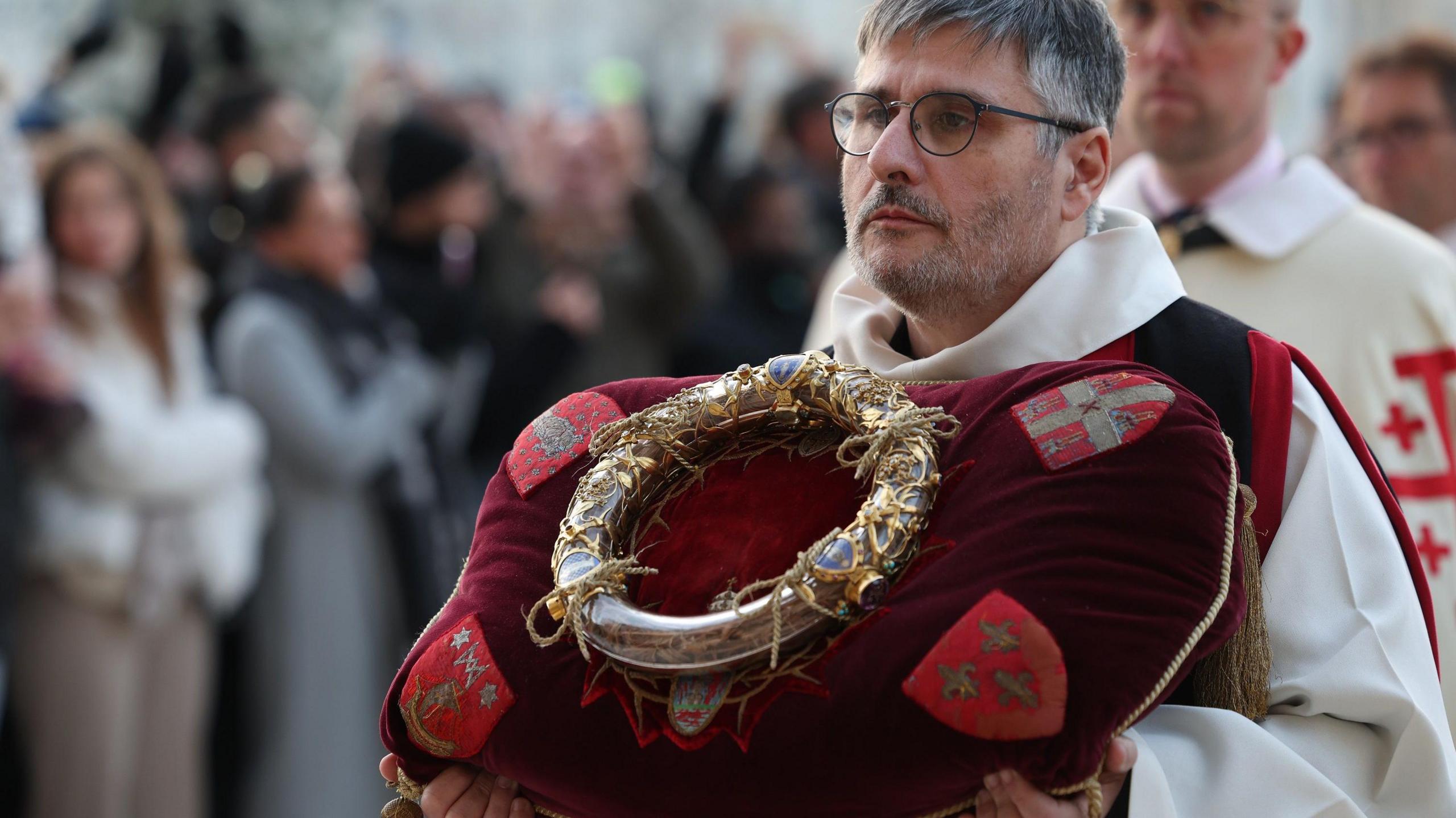 A knight of the Order of the Holy Sepulchre holds the Crown of Thorns on a cushion during a procession to the Notre-Dame Cathedral. 