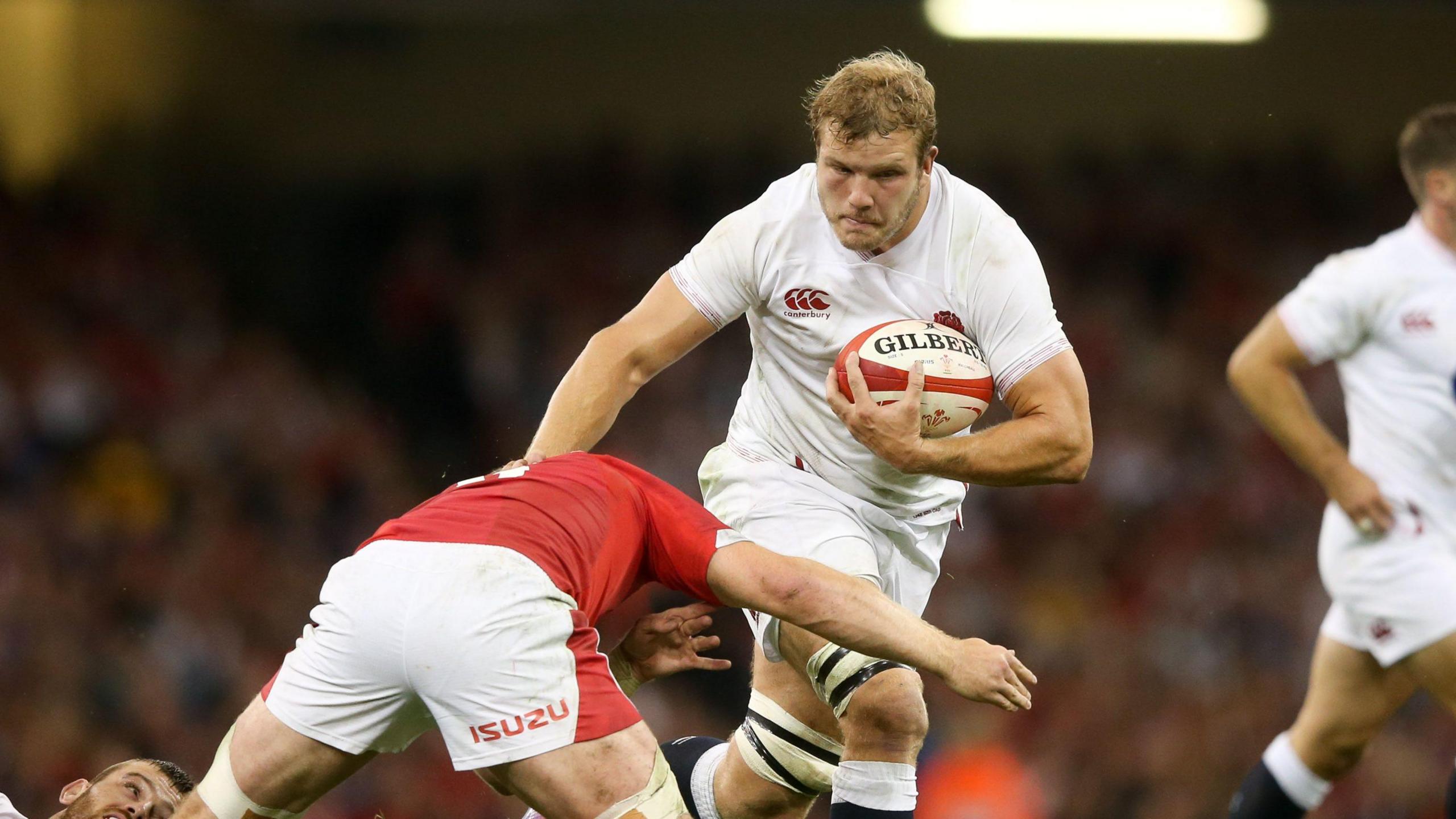 Joe Launchbury runs with the ball under his left arm for England