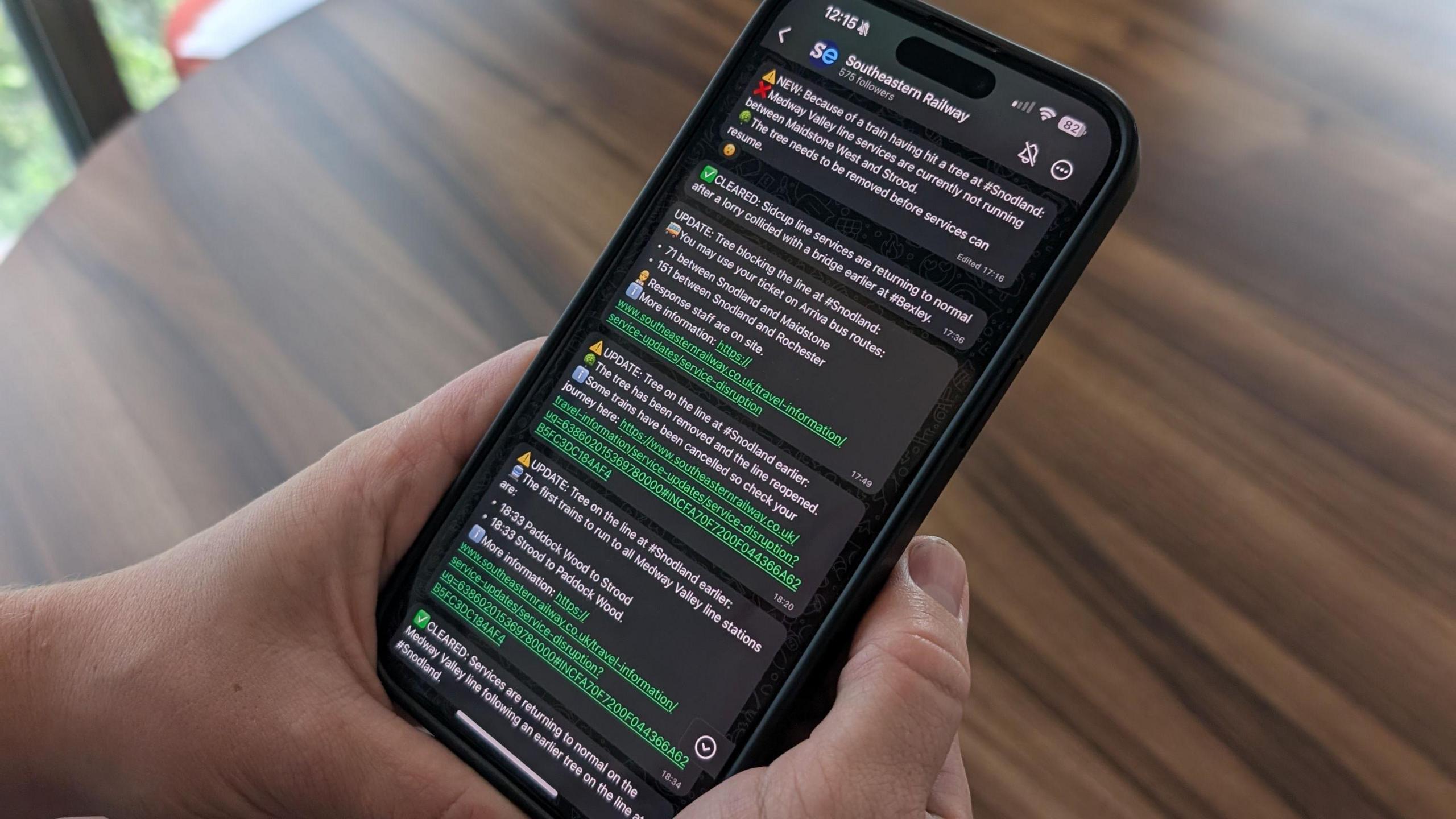 Close up of hands holding a phone with the screen showing WhatsApp updates