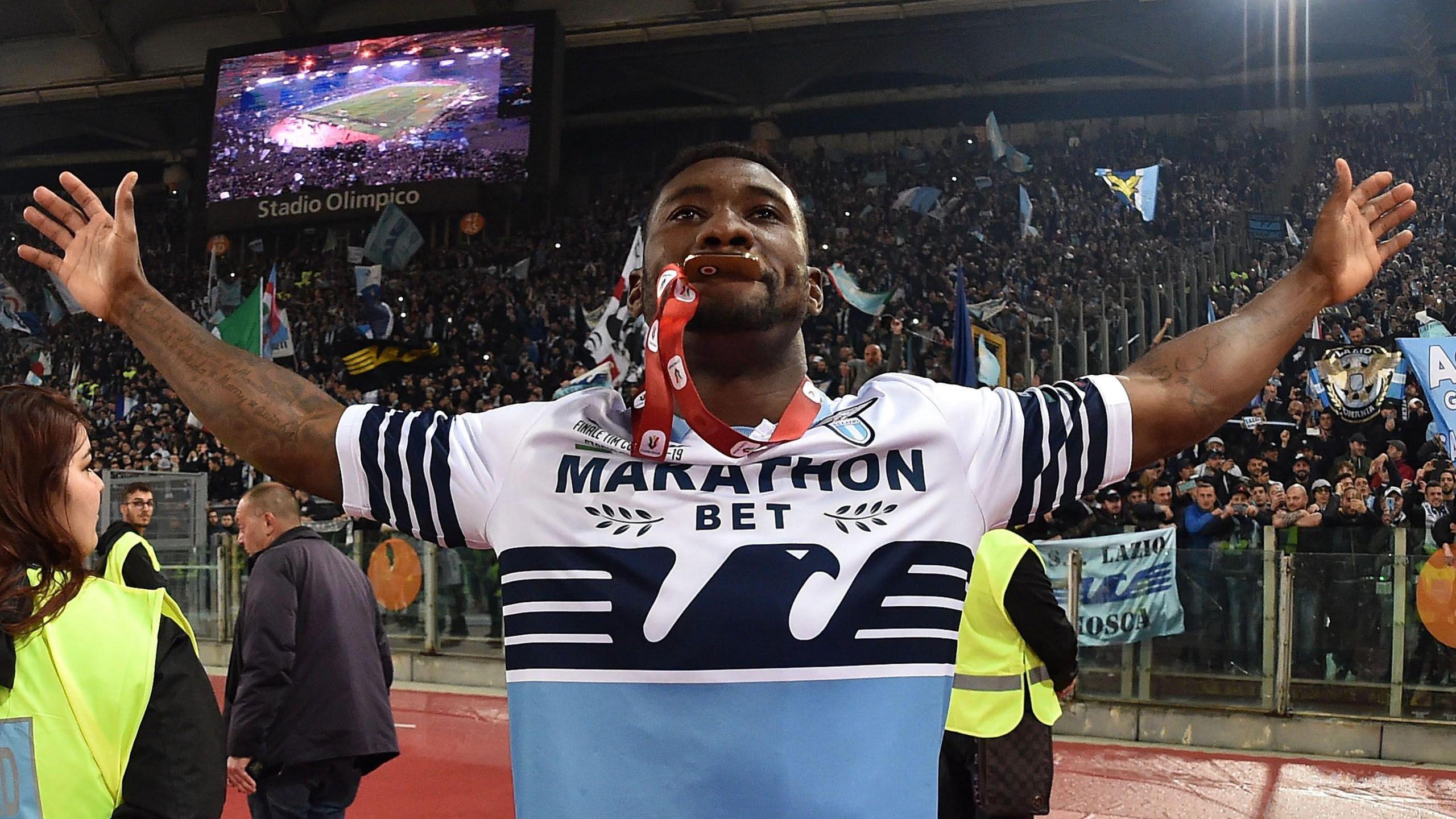 Bastos poses with a winners' medal in his mouth and his arms stretched out wide as he celebrates in front of Lazio fans at the Stadio Olimpico in Rome