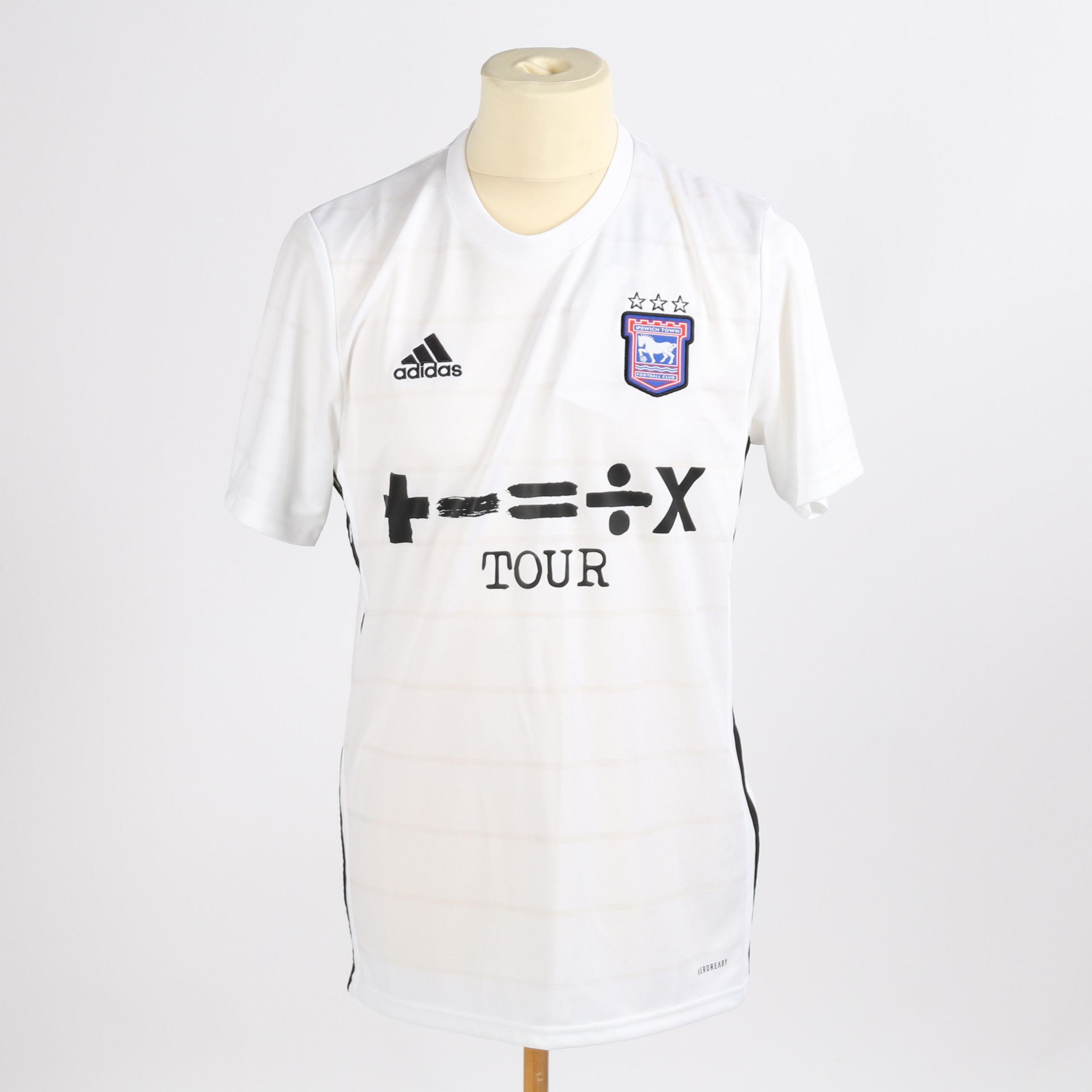 A general view of Ed Sheeran's Ipswich Town away shirt from the 2021/22 season. It is a white football shirt with the club's logo on the upper right hand side and the Adidas brand logo on the upper left hand side. Ed Sheeran's Divide album logo is in the middle of the shirt.