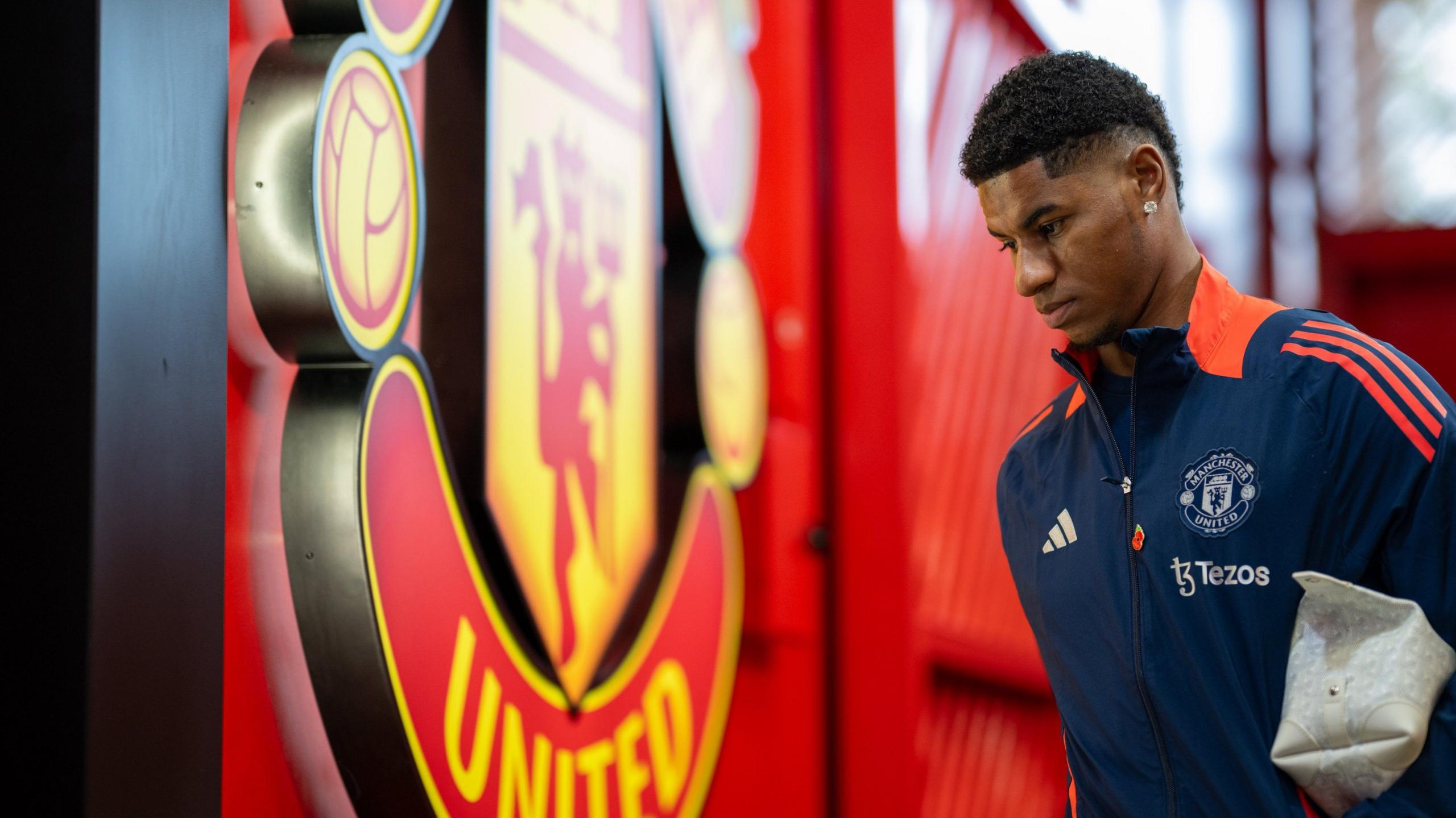 Marcus Rashford pictured in Manchester United tracksuit with a washbag under his arm