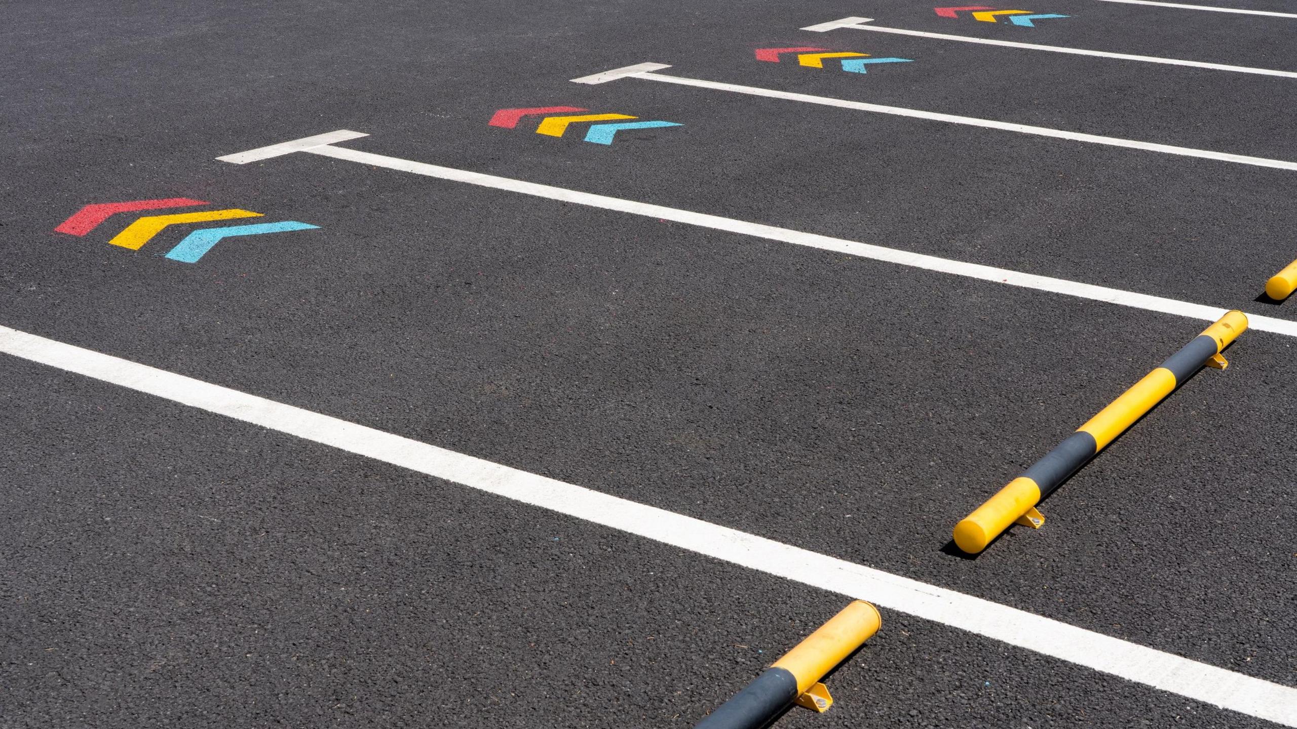 Several parking spaces, with the same markings in each one - three arrows coloured red, yellow and light blue