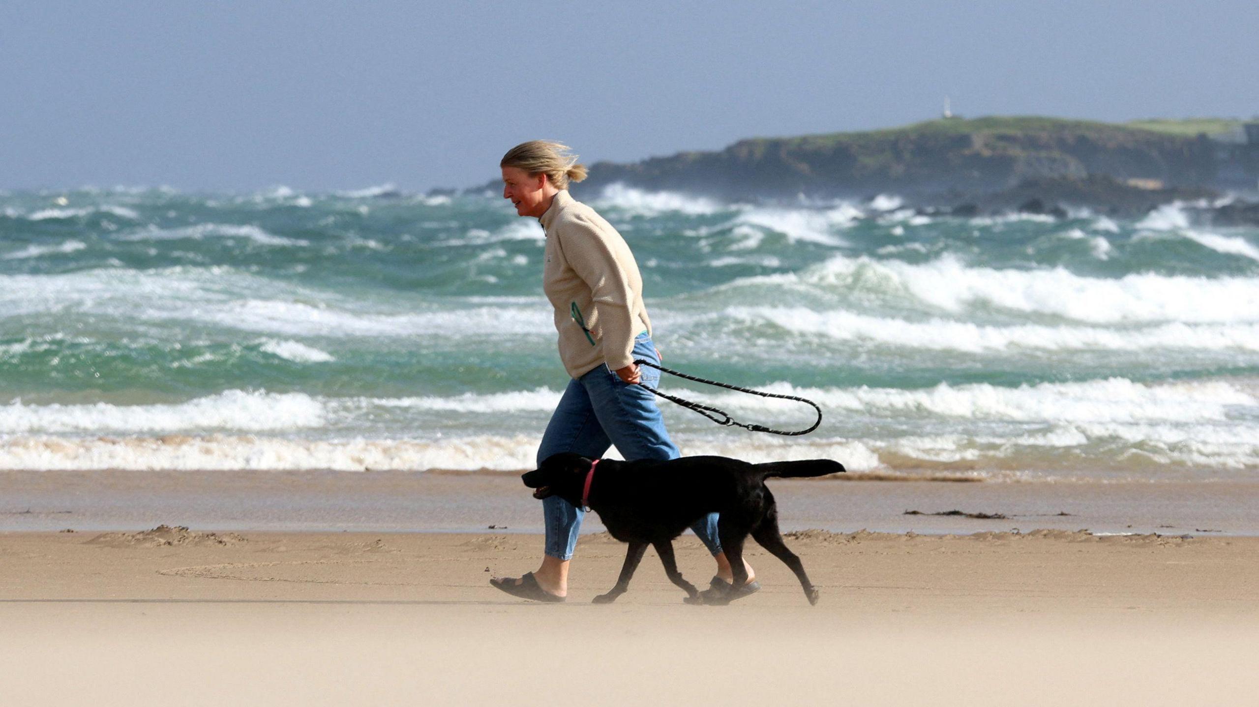 A person walks their dog during Storm Floris on the north coast of Northern Ireland, Portstewart, 4 August 2025. REUTERS/Cathal McNaughton.
