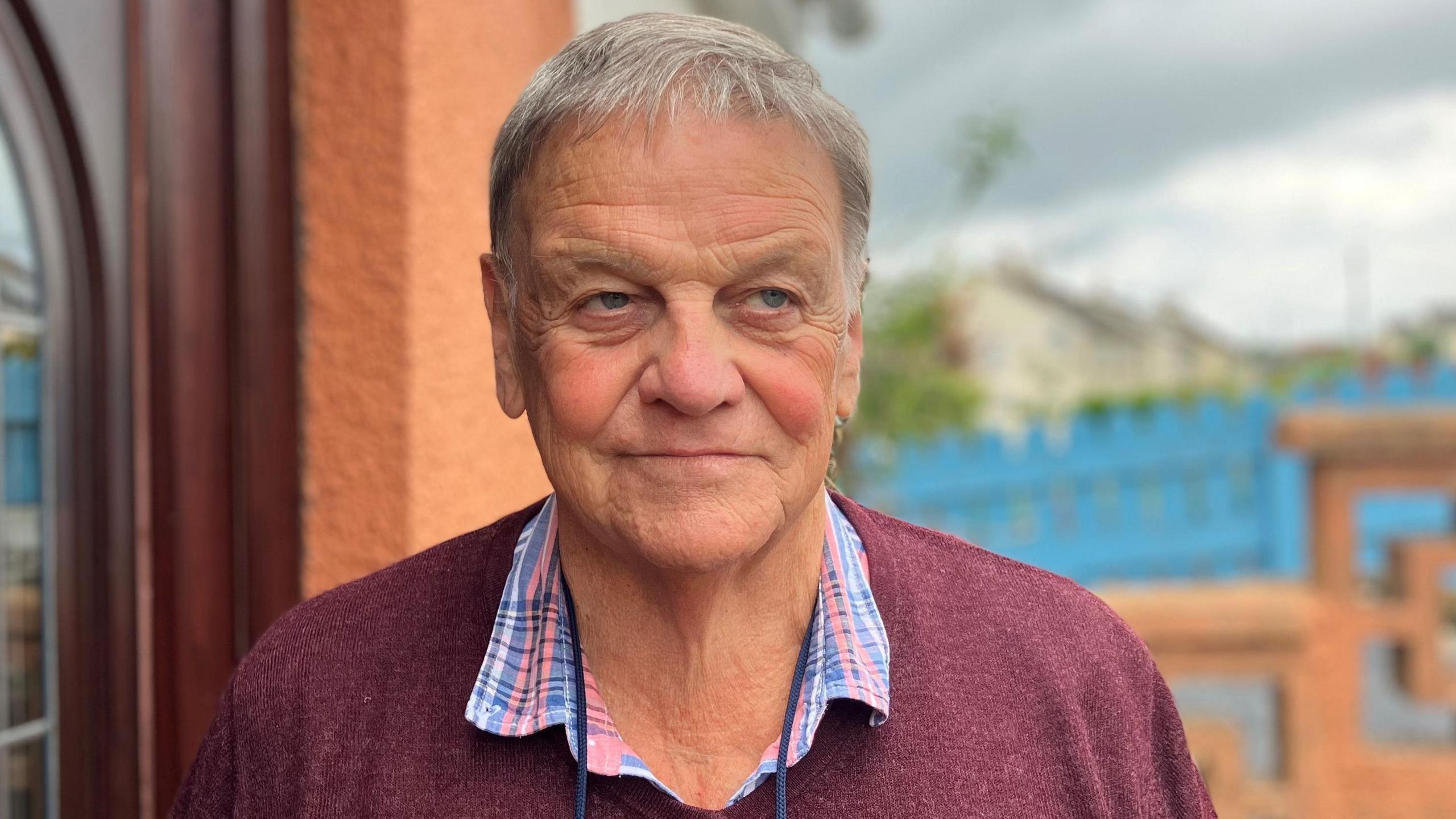 Older man with grey hair looking disgruntled away from the camera