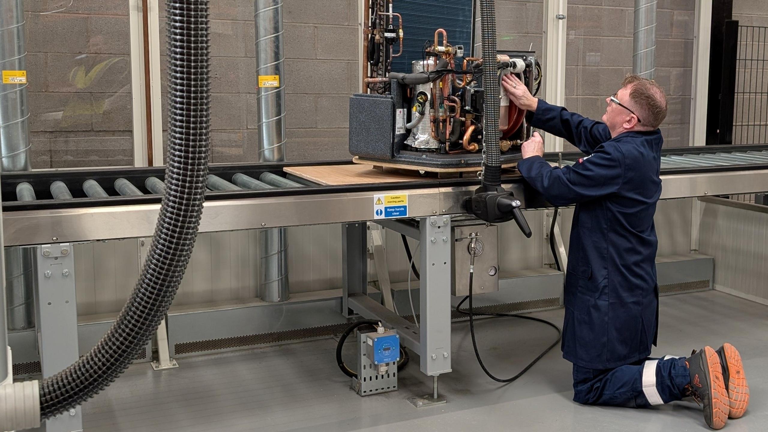 A man kneeling works on an Octopus heat pump