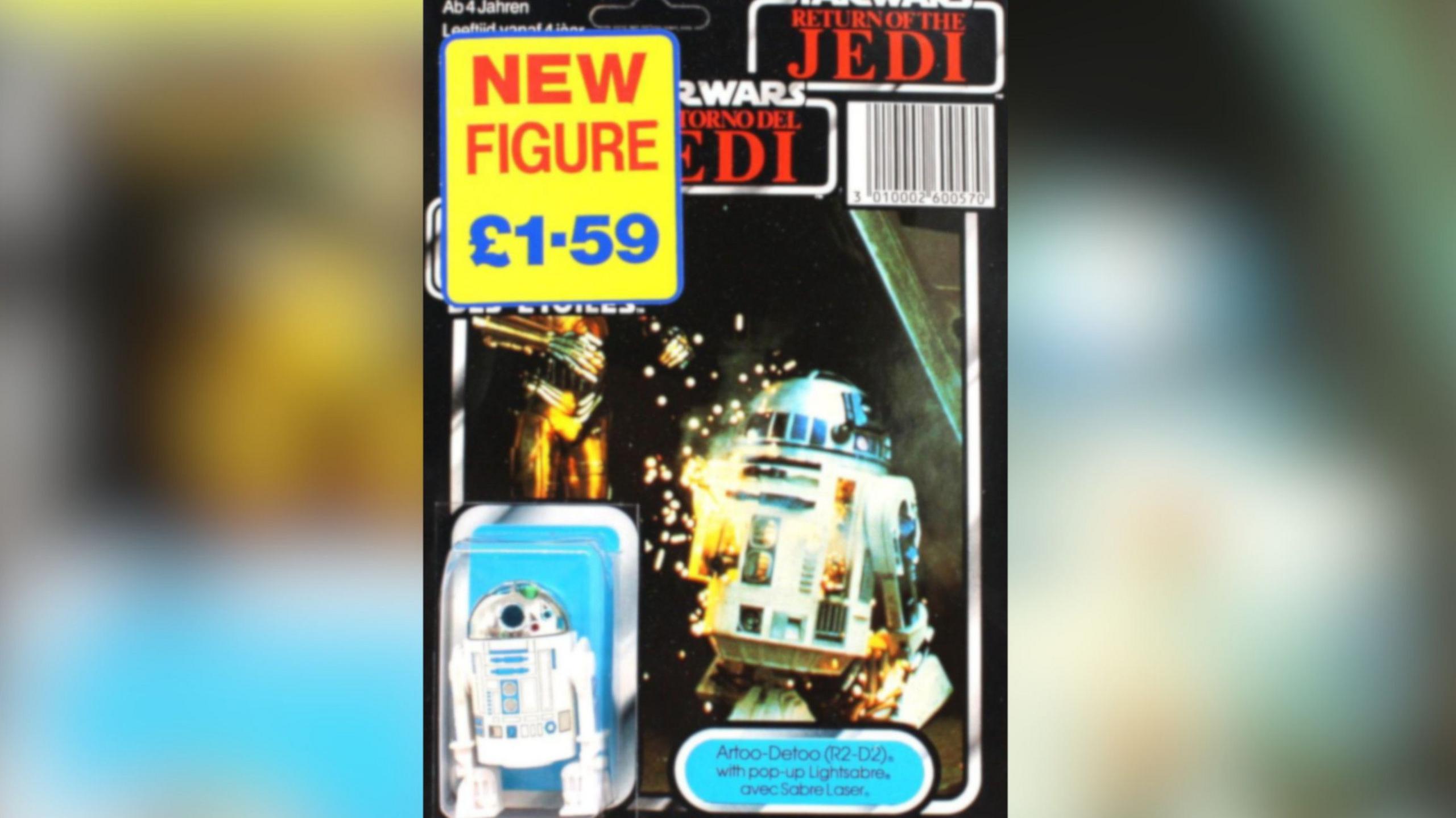 A R2D2 toy figurine, with a price tag on, showing a small blue and white robot, and an image of him from the Star Wars film, next to the figurine.