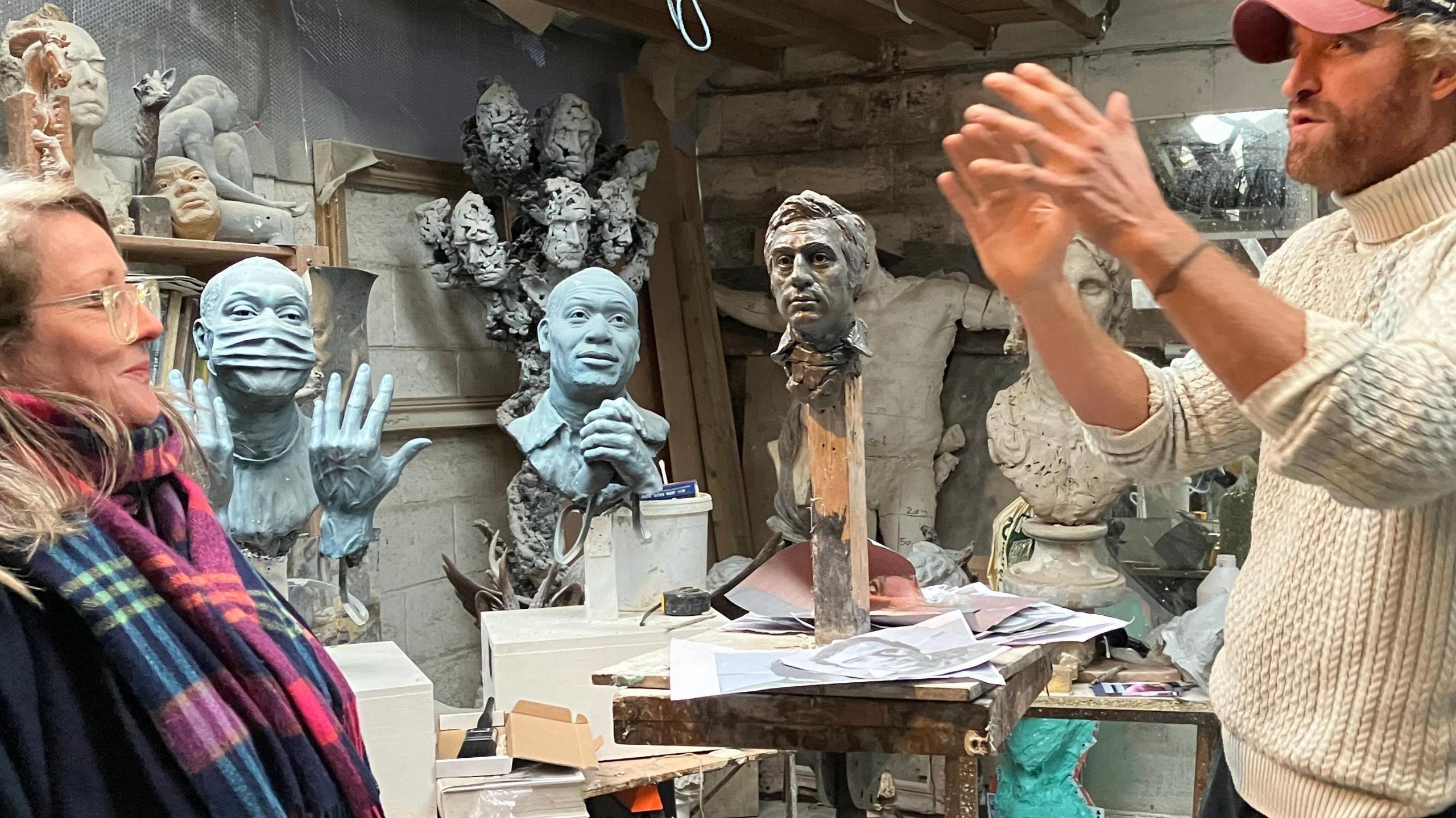 Nick Elphick gestures to Sally Jones in front of rough clay bust of Terry Jones