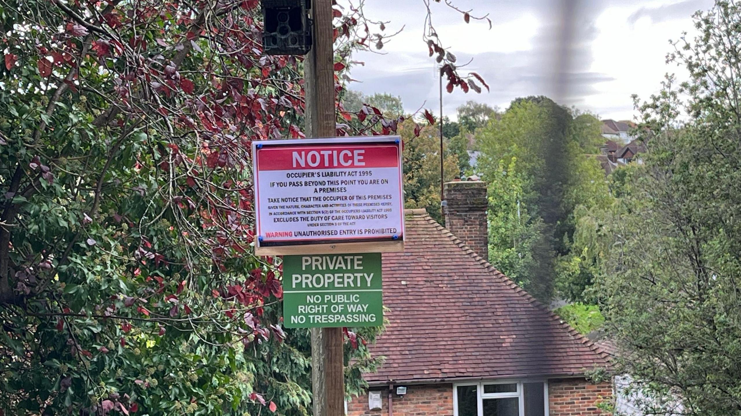 Signs which say private property and a camera near the entrance to the pathway