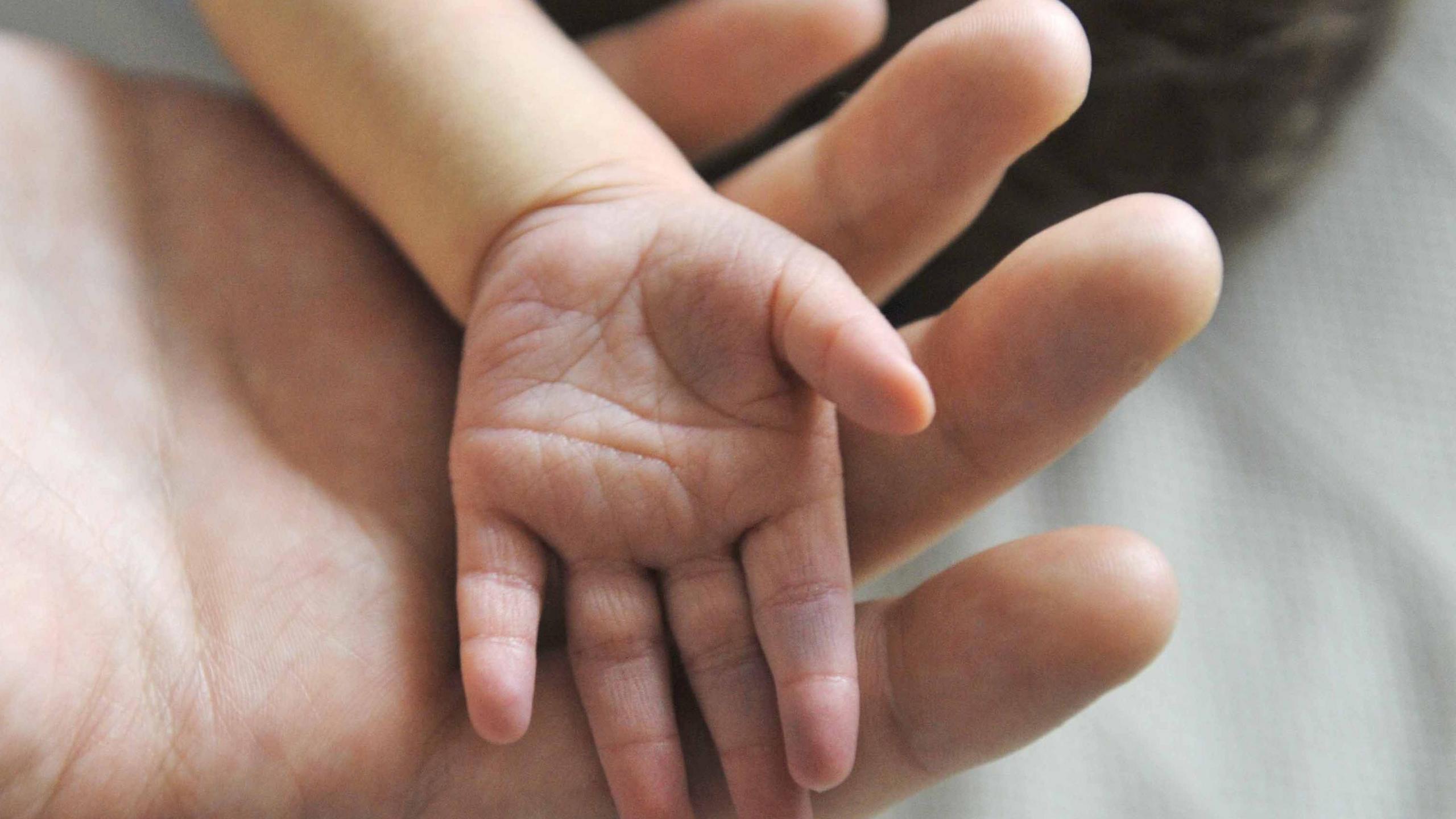 A baby's hand on a larger hand. 