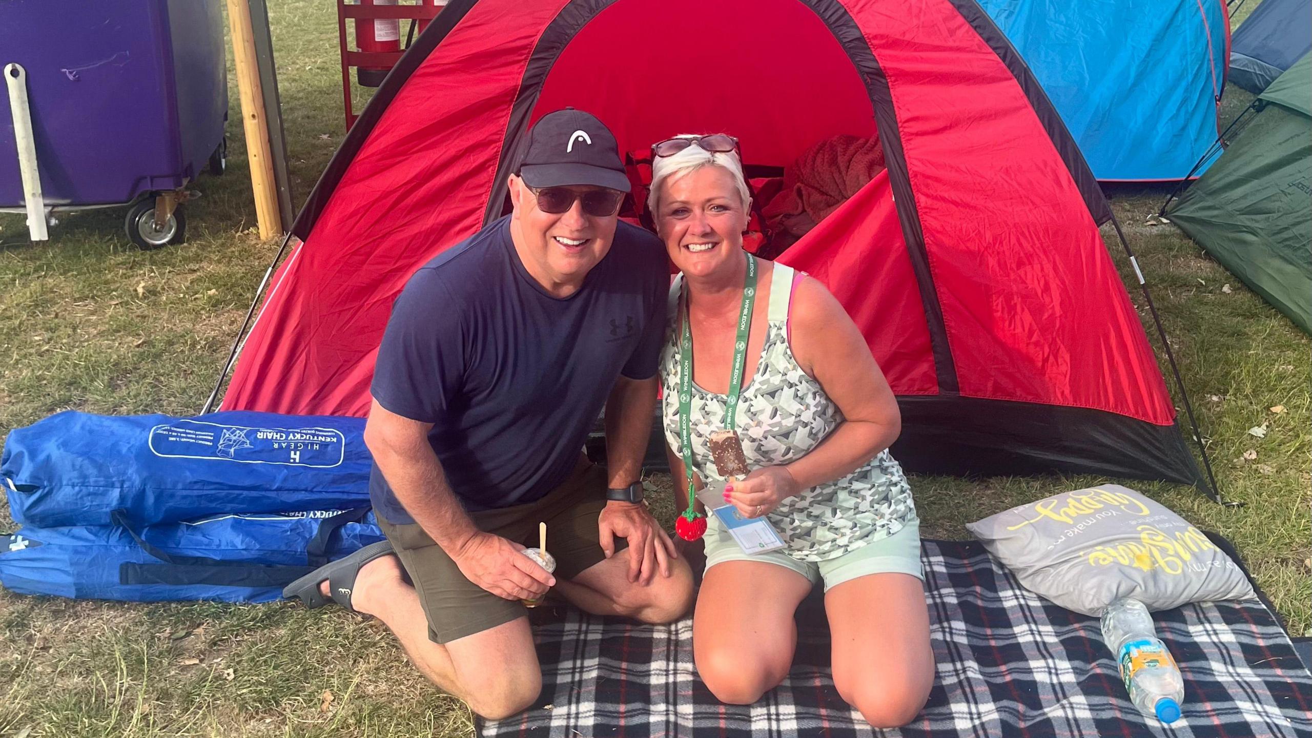Nigel and Vicki Broad from Wales sit on a picnic rug in front of their tent as they queue at Wimbledon