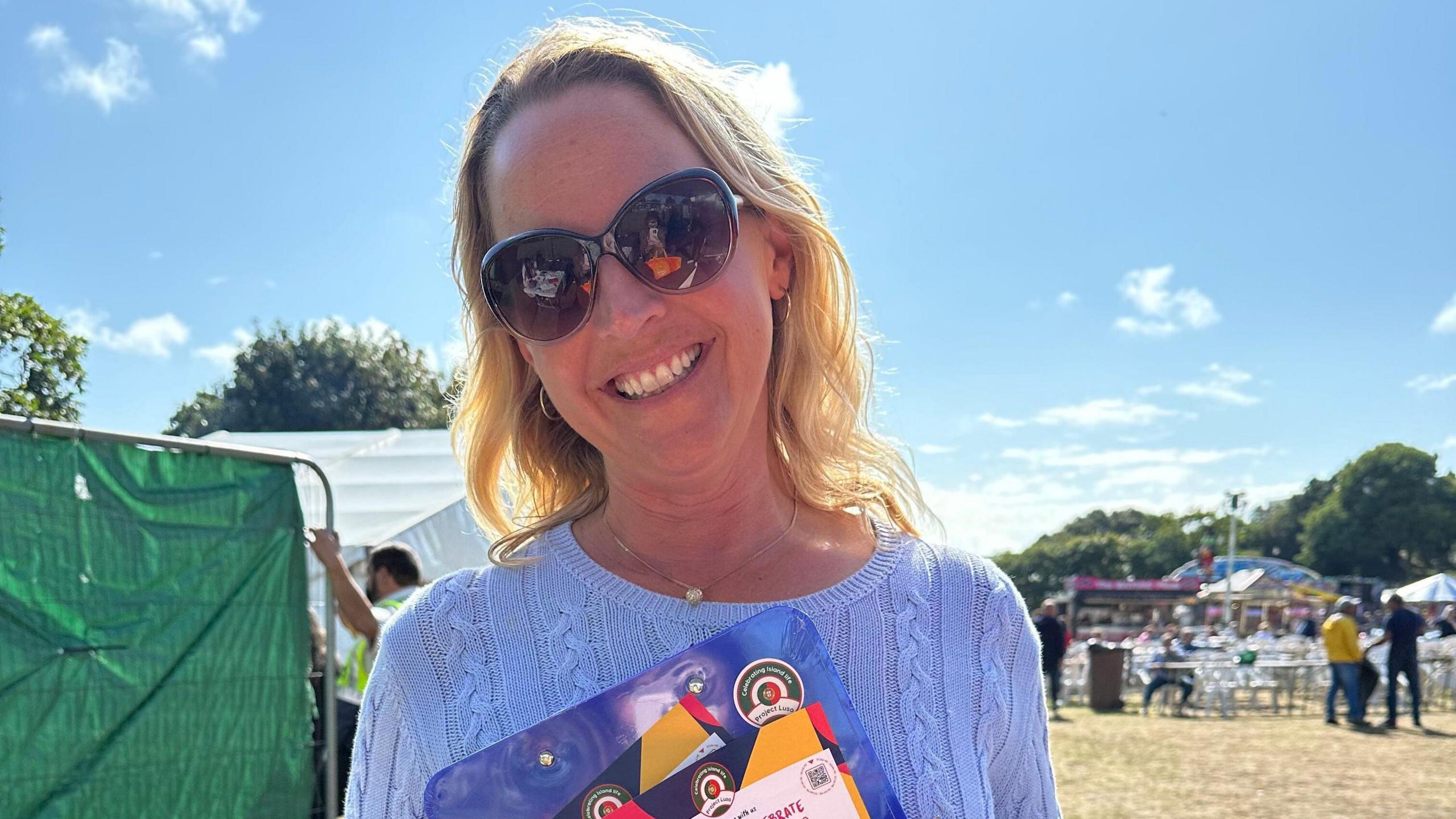 Kate Wright, chair of the Jersey Community Relations Trust, stands in a field with leaflets on the project 