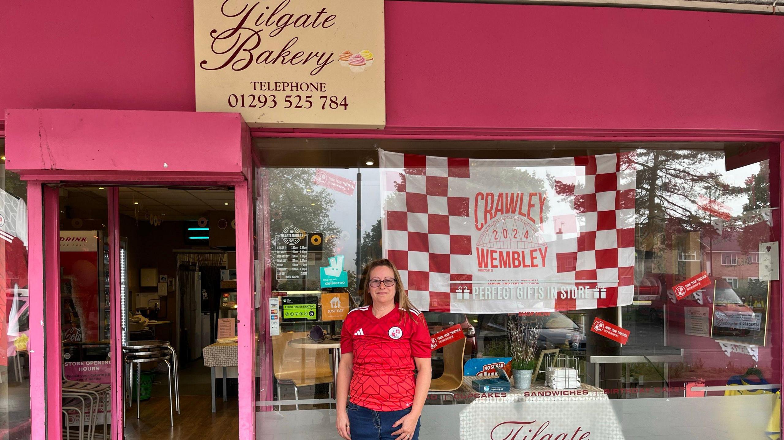 Jane Kirkham with a Crawley flag in the window of her bakery