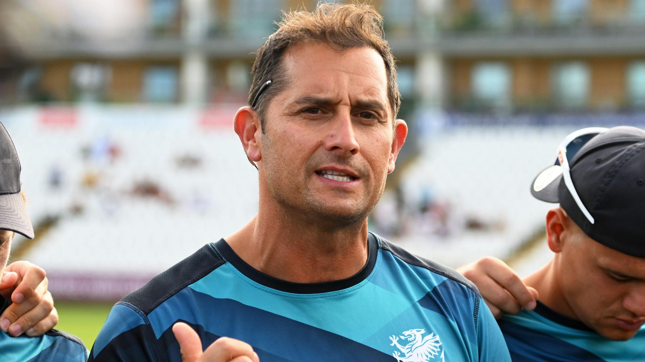 Jason Kerr, wearing a Somerset training top with navy blue, blue and light blue patterns and a white Somerset badge, while talking to his players before a T20 game against Glamorgan at the County Ground