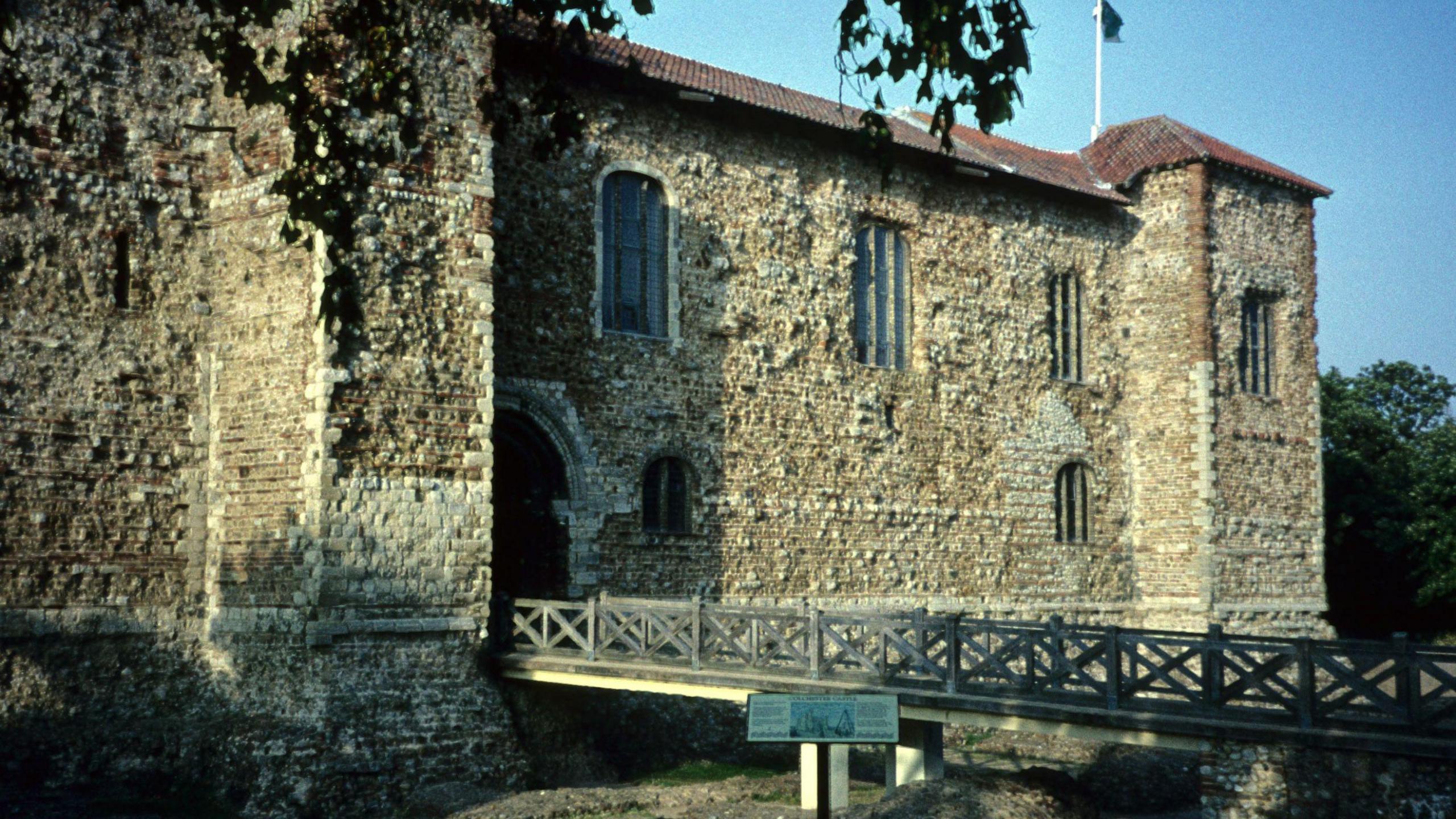 A castle which fills the screen, the bricks are course and uneven, a bridge stretches across the image