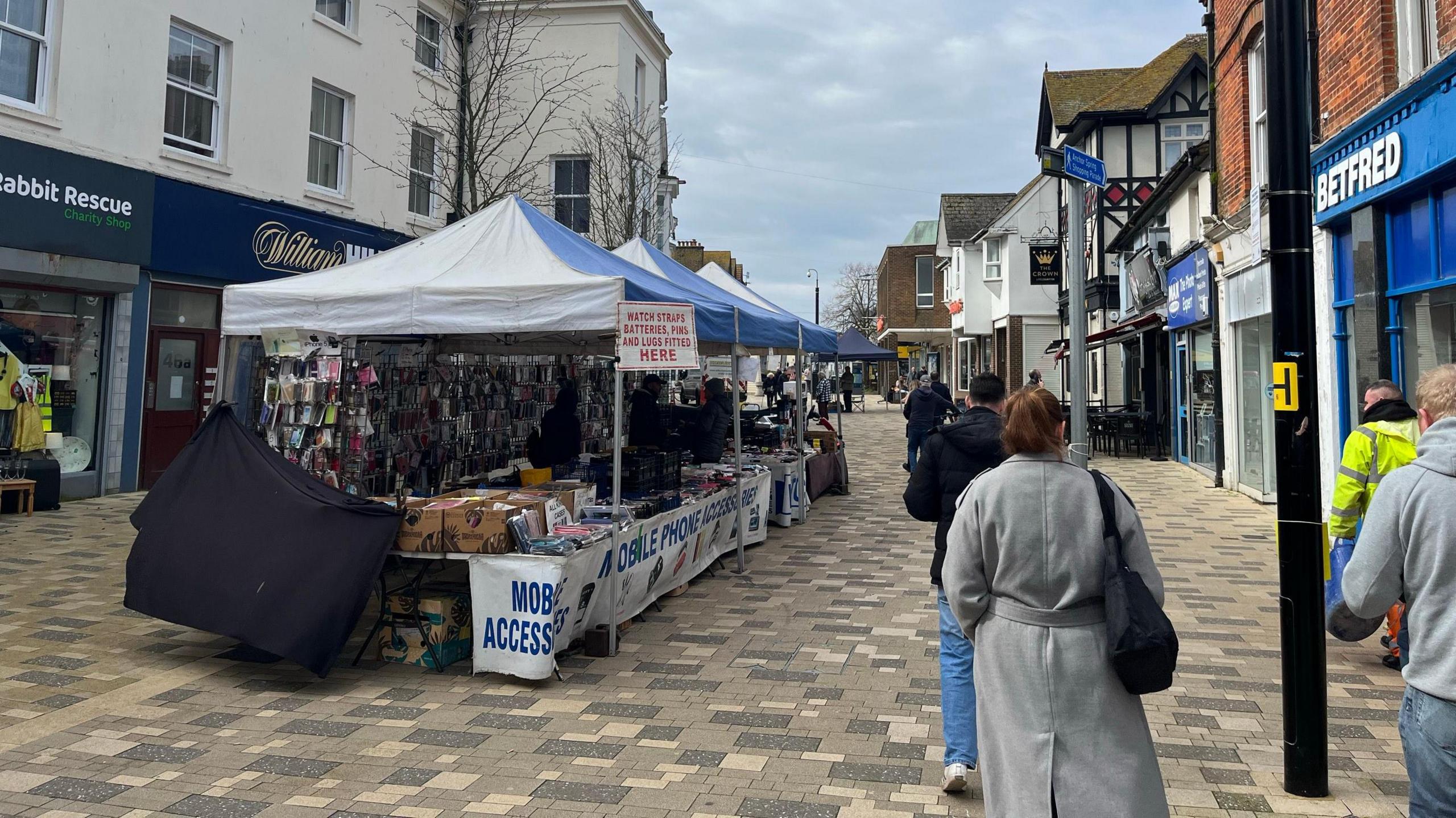 People walking along market stalls at a town centre.