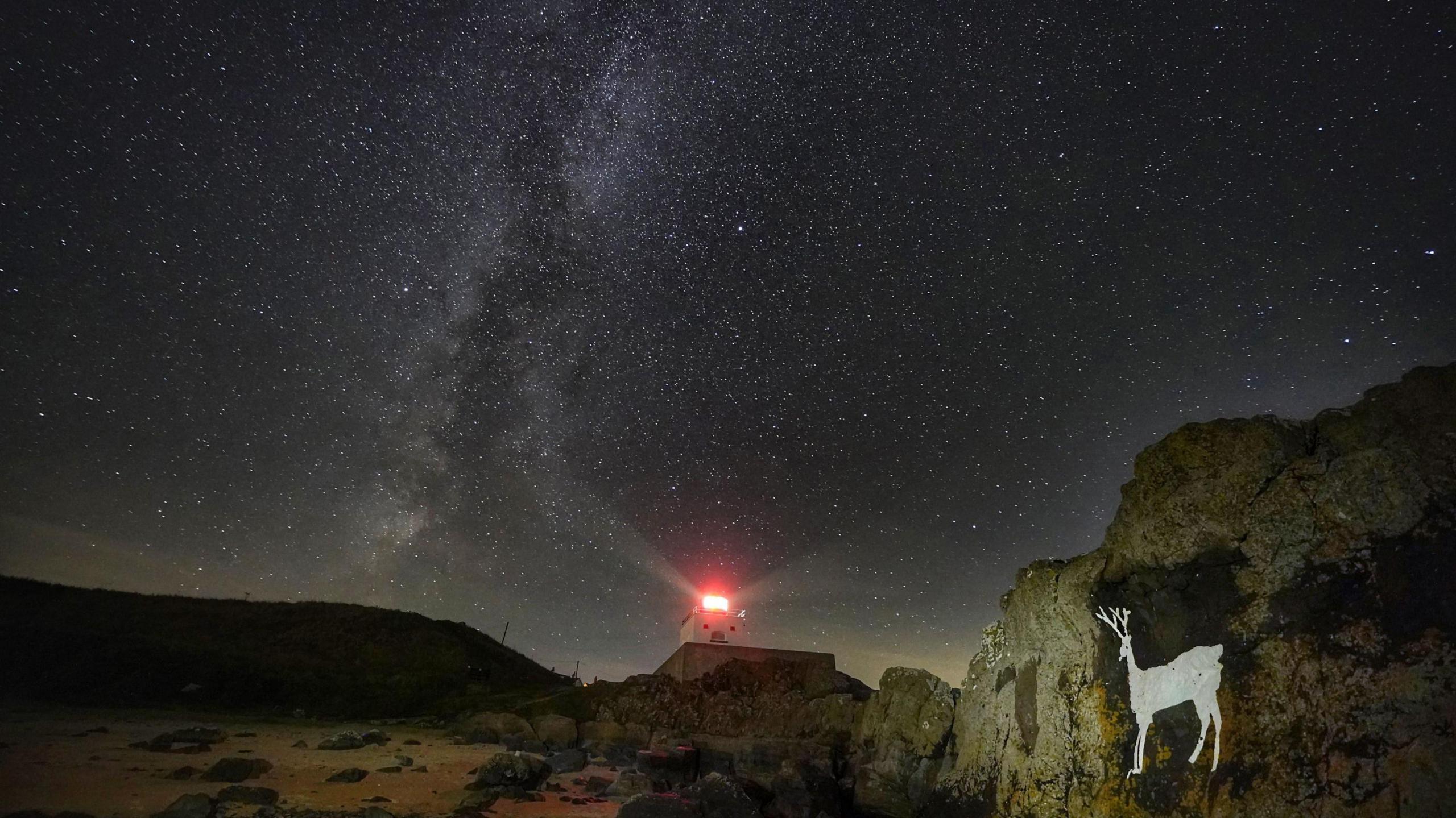 The milky way illuminated over a lighthouse