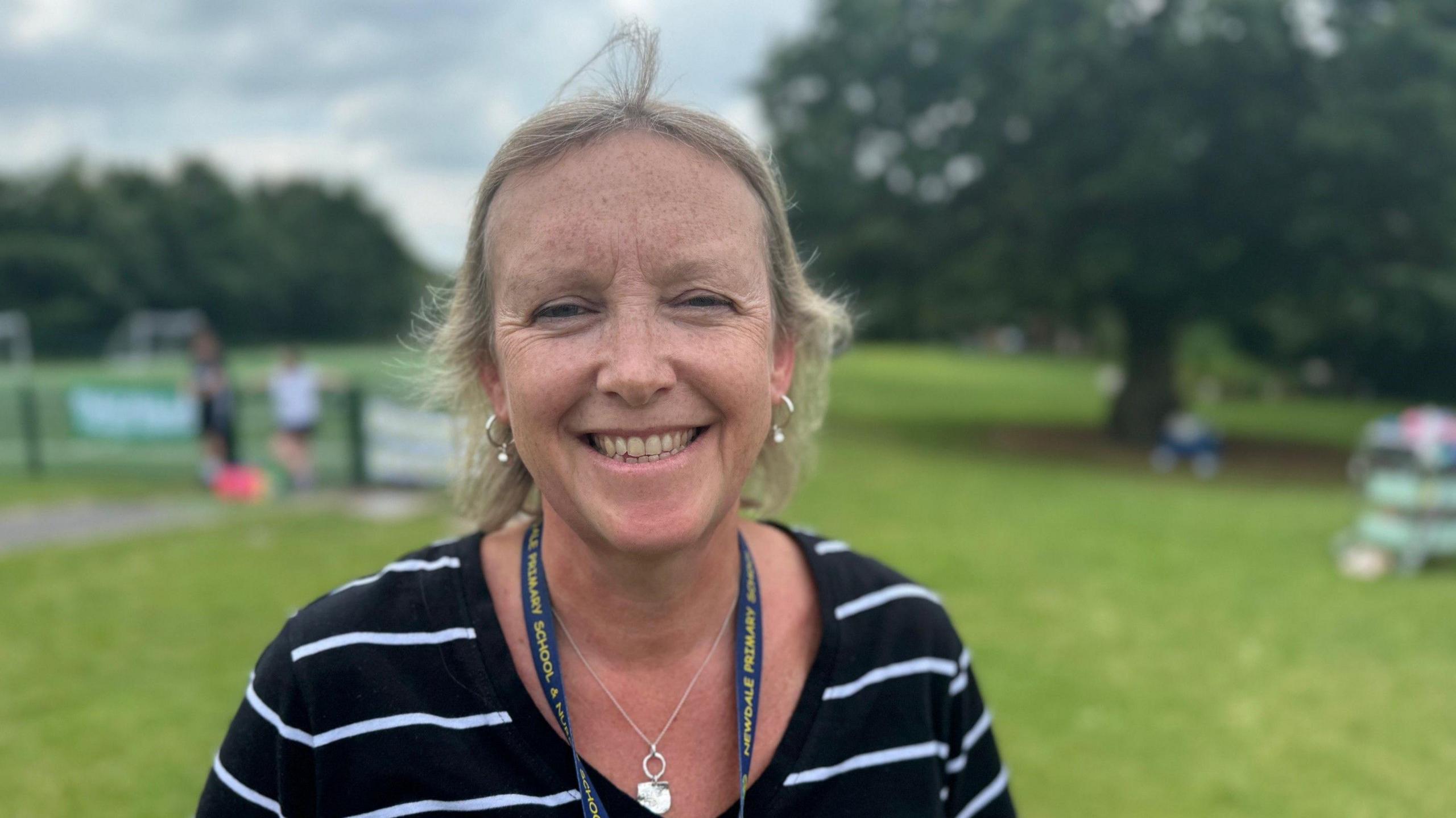 Headteacher Rachel Cook is wearing blue and white striped top and is smiling into the camera.