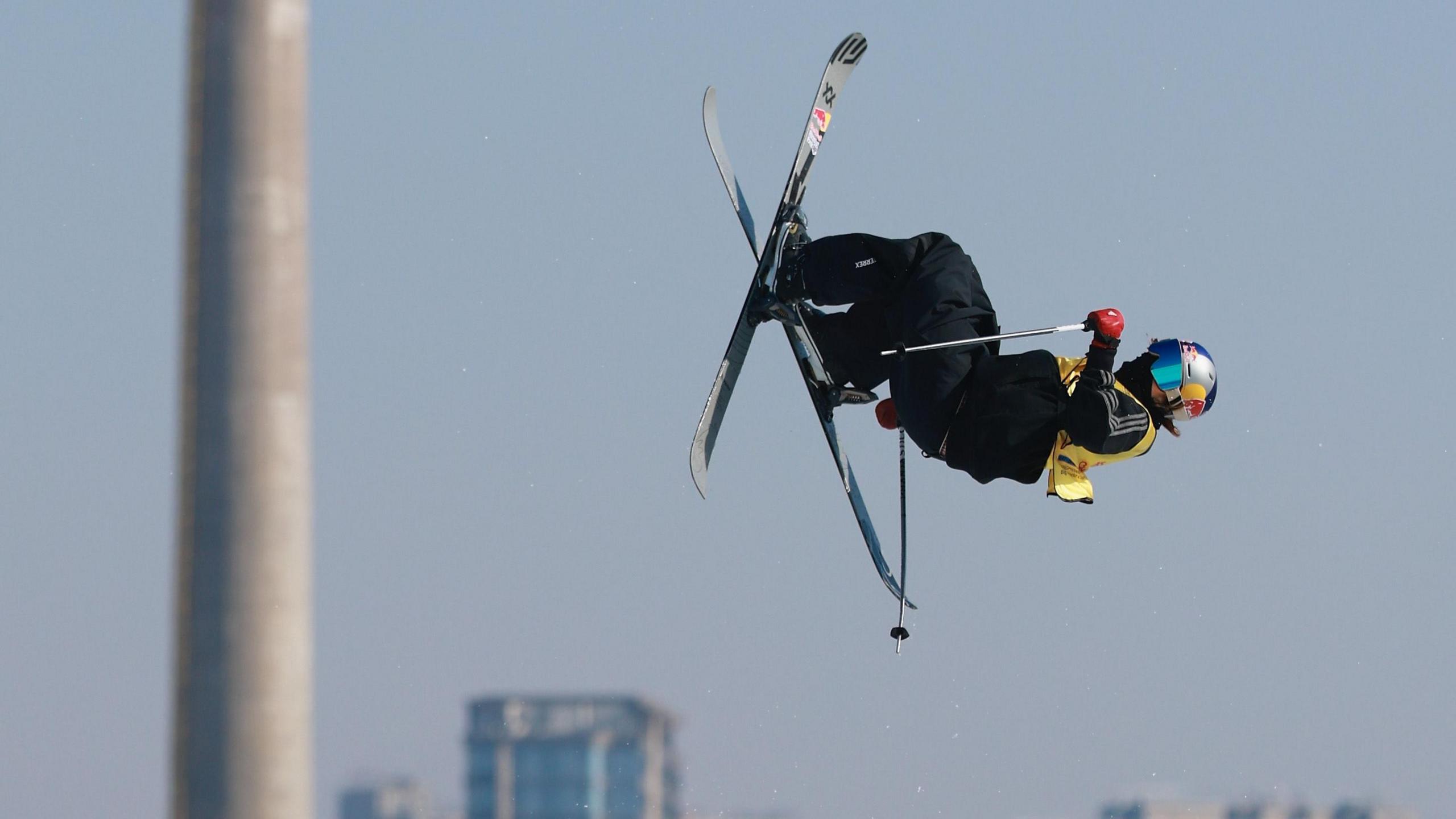 Kirsty Muir in the air on her skis, with a tower and other buildings blurred in the background
