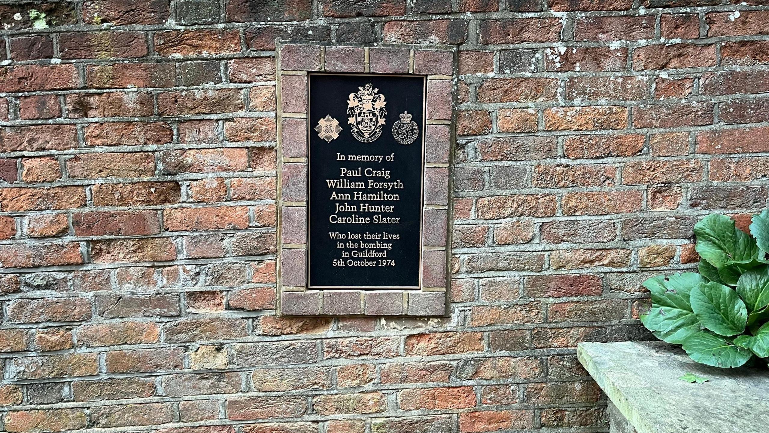 A bronze plaque commemorating those who died is set into the wall of Quakers acre on North Street in Guildford