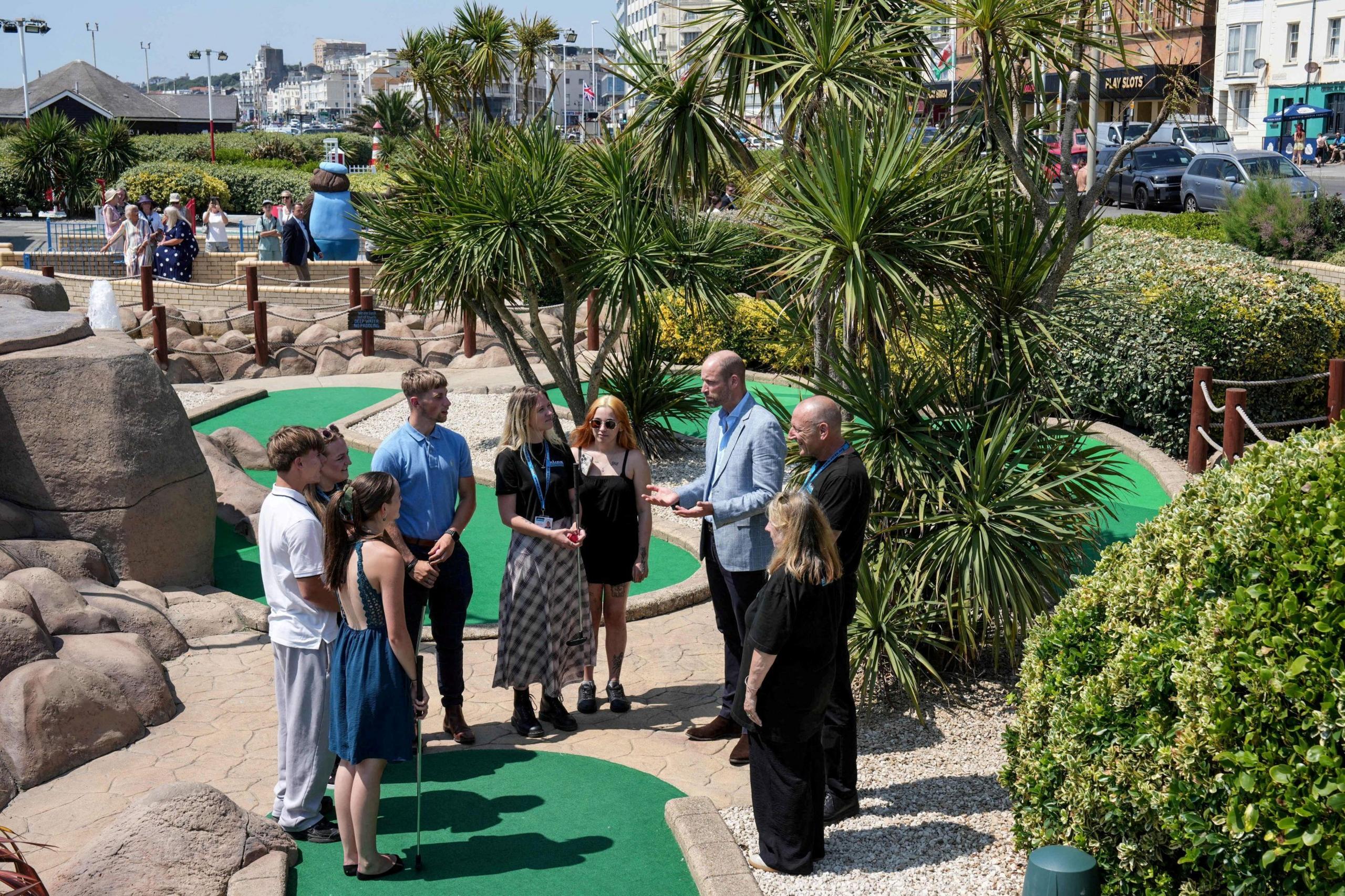 Prince William stands in a group of people on a crazy golf course