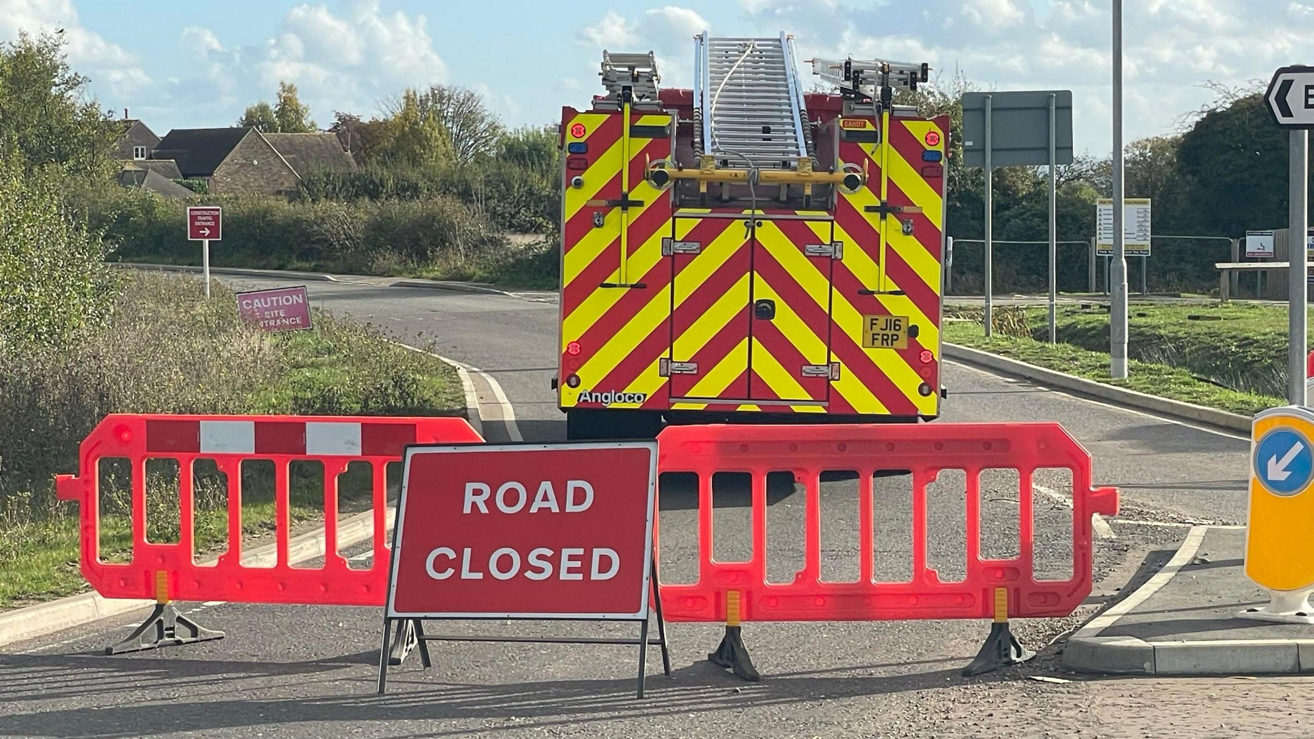 Road closed sign with barriers and a fire engine behind it. The road has been blocked off at a junction.