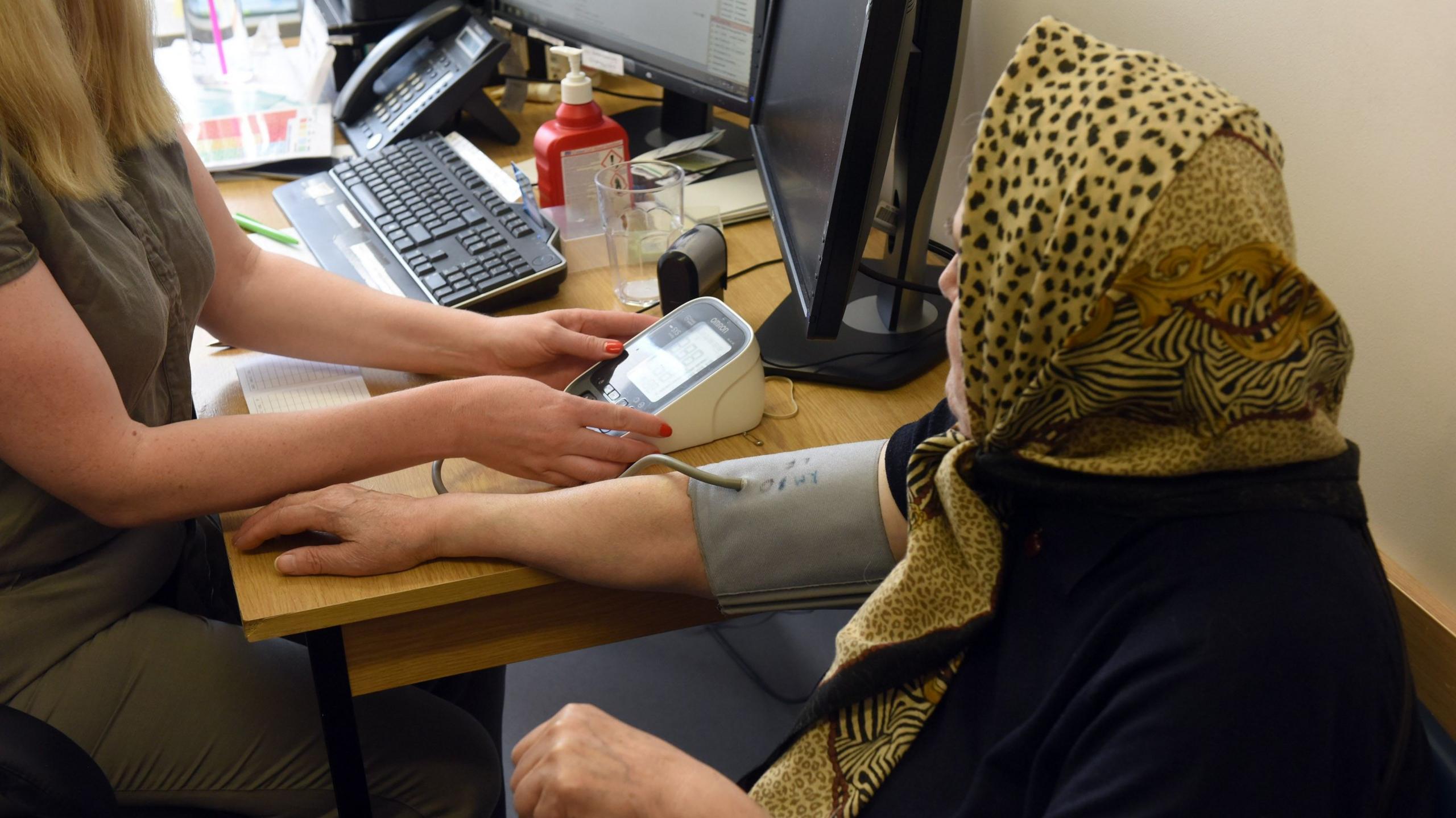 A GP takes the blood pressure of a patient 