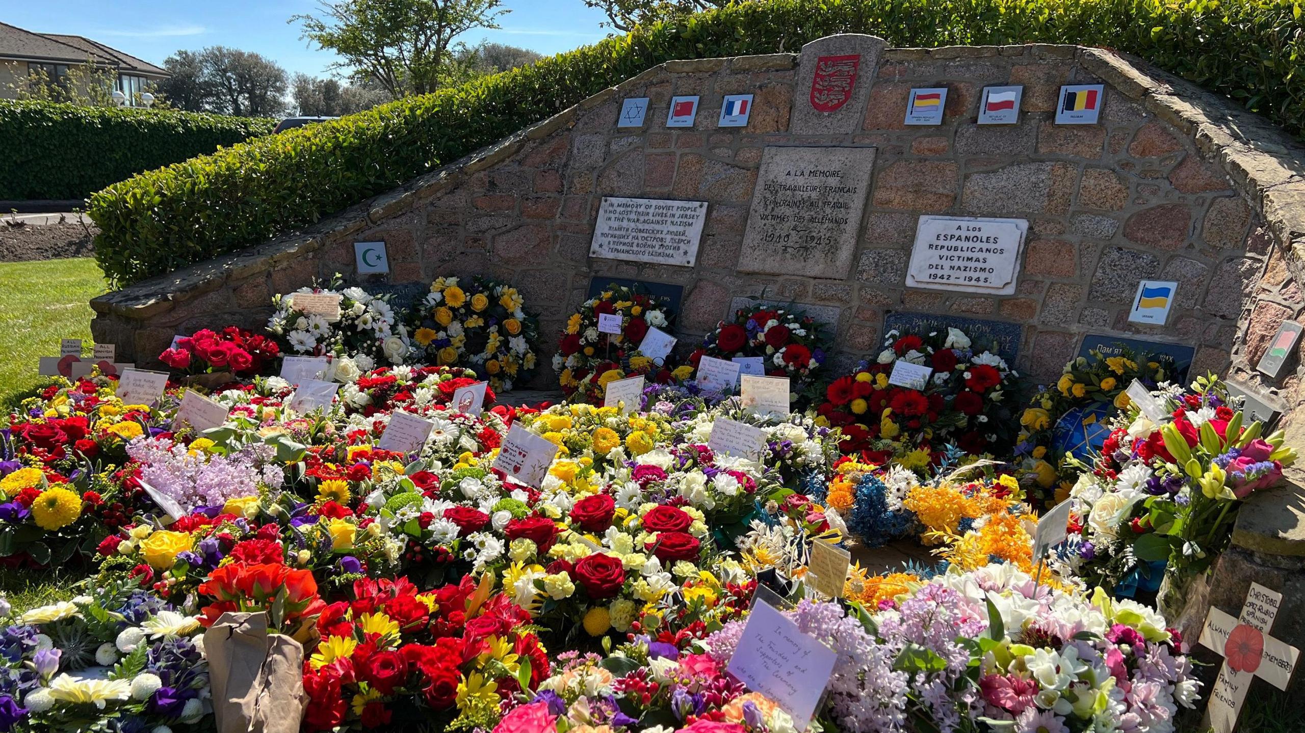 Wreaths of flowers are laid out on the ground with many containing special messages from families and loved ones